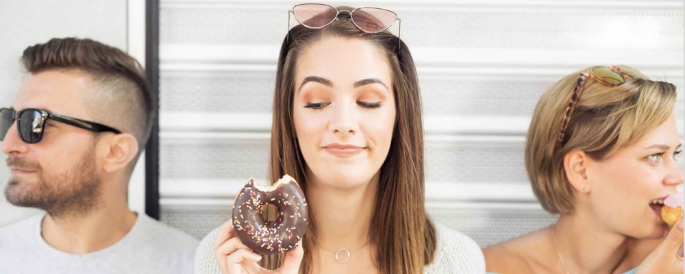 Women sitting with friends contemplating eating a donut 