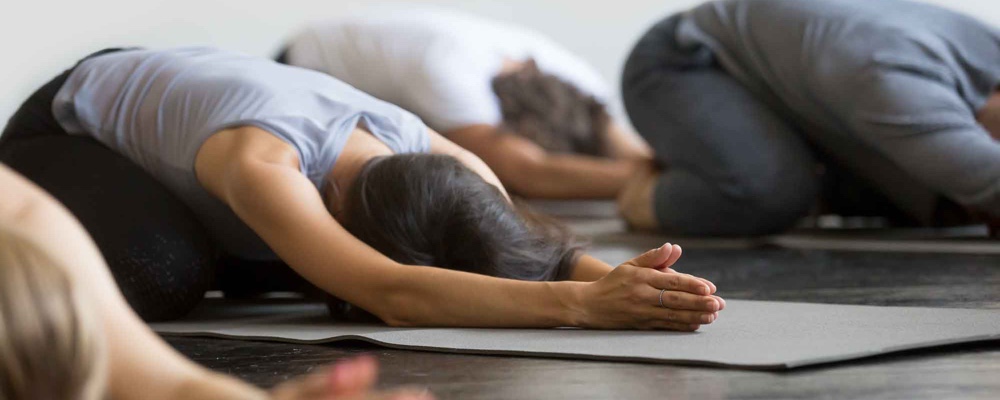 Group of people in yoga class sitting in child pose