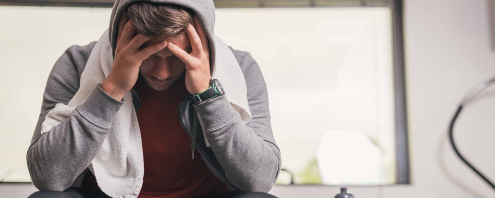 Man sitting down after work out with headache   