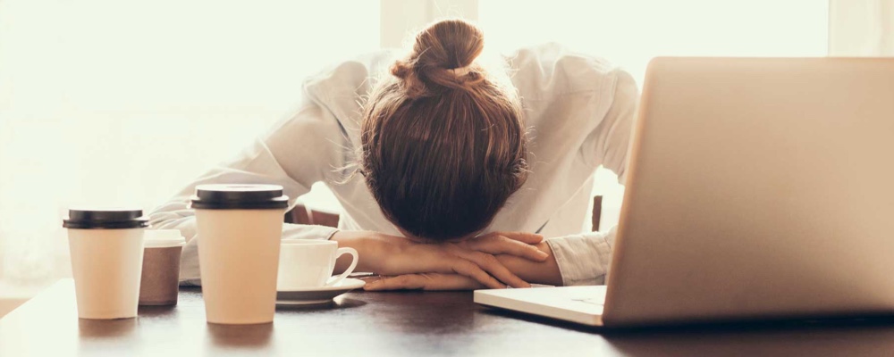 Stressed woman at work with head down on desk