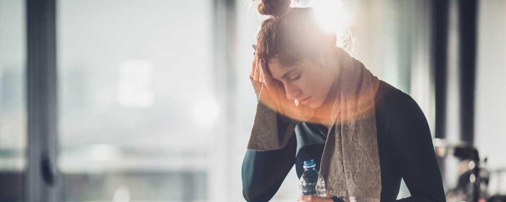 Woman exhausted taking a water break after riding exercise bike. 