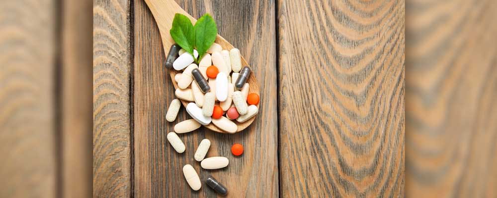 supplement pills on a wooden spoon