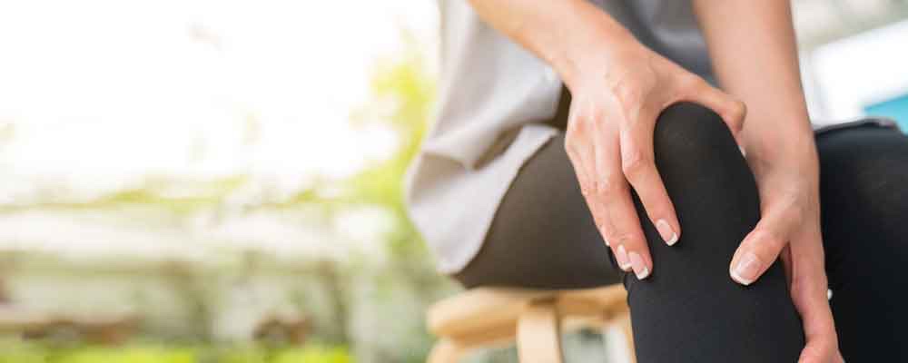 A young woman massaging her painful knee