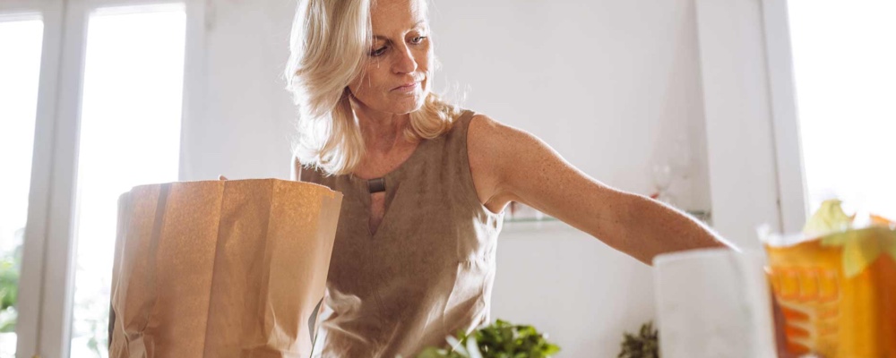 Woman in kitchen unpacking healthy groceries