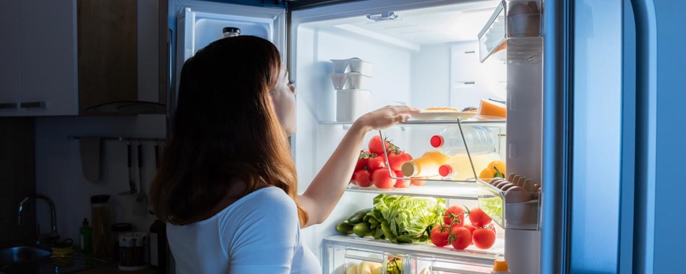 Woman staring into a fridge full of food