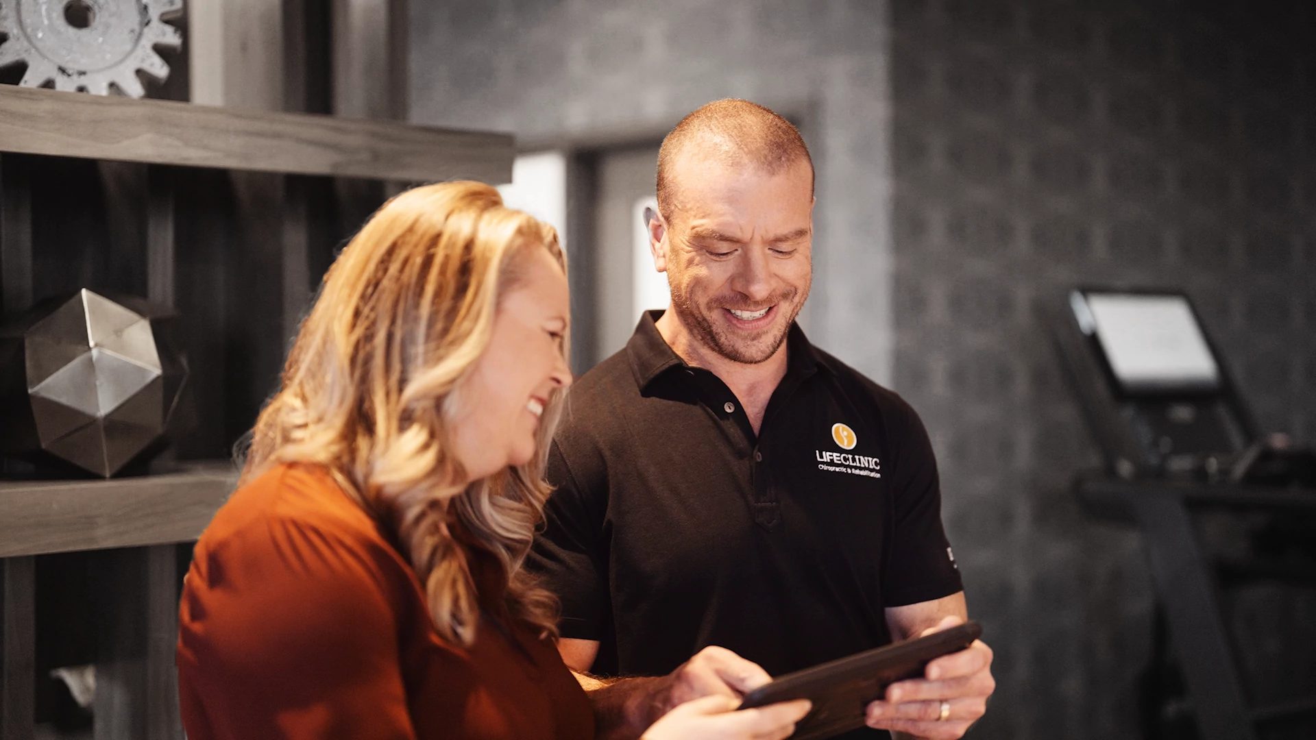 A LifeClinic chiropractor looking at a digital tablet with a patient