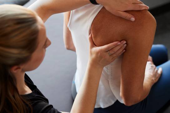 Chiropractor examining a female clients shoulder