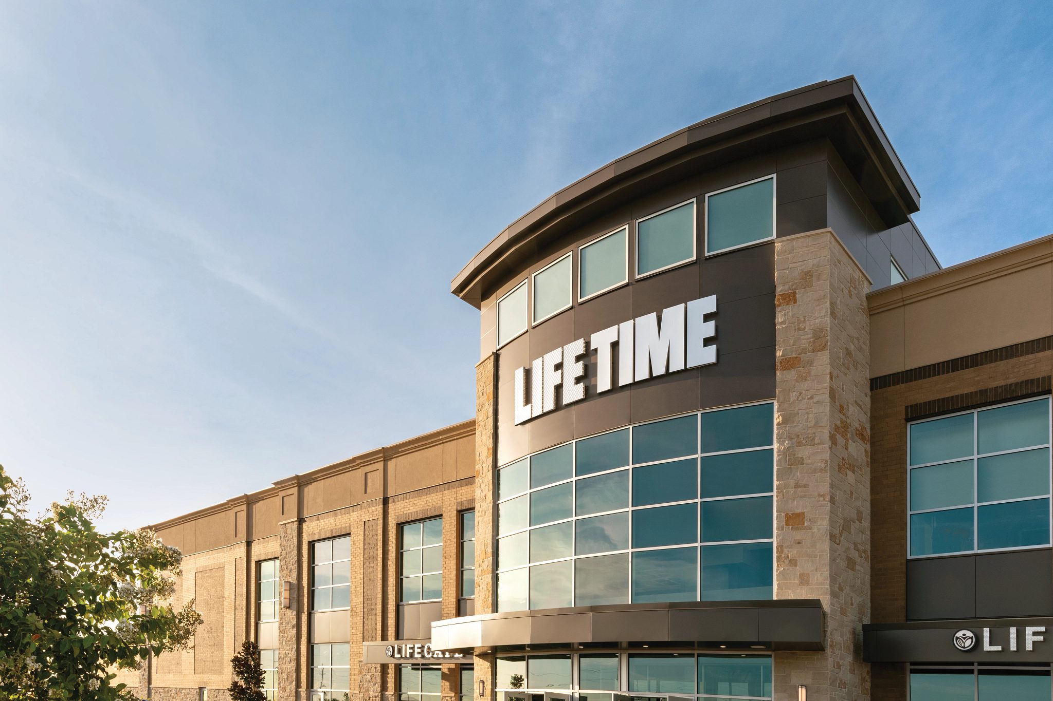An exterior view of a Life Time Athletic building under a clear, blue sky