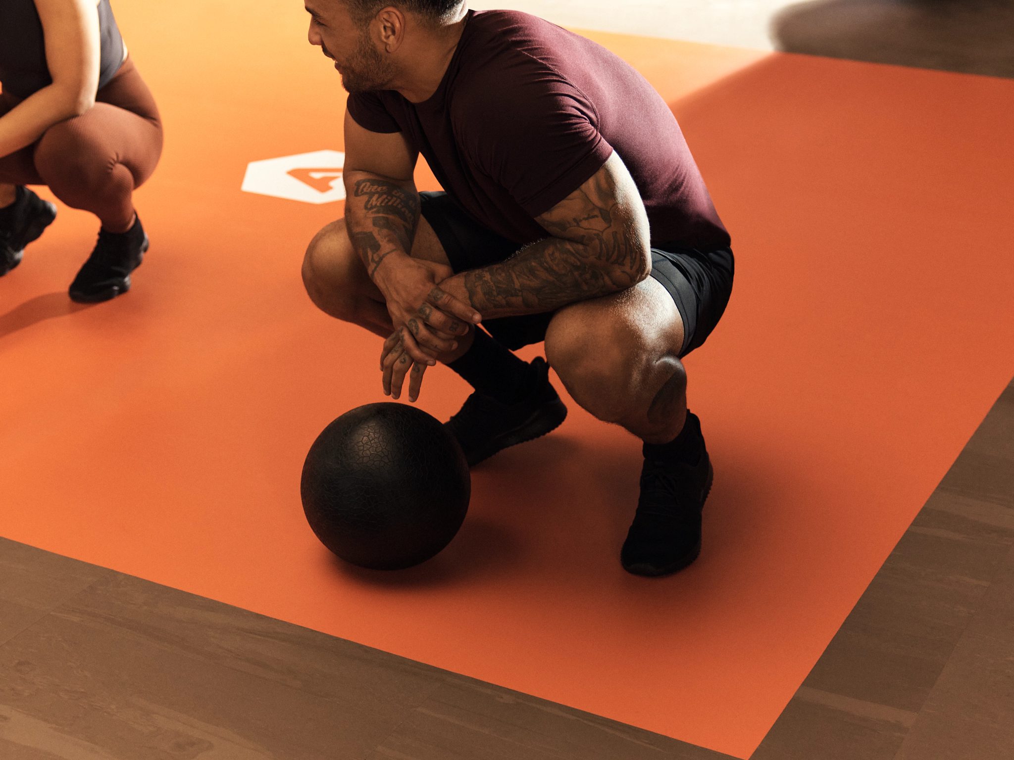 Alpha class member squatting next to a medicine ball