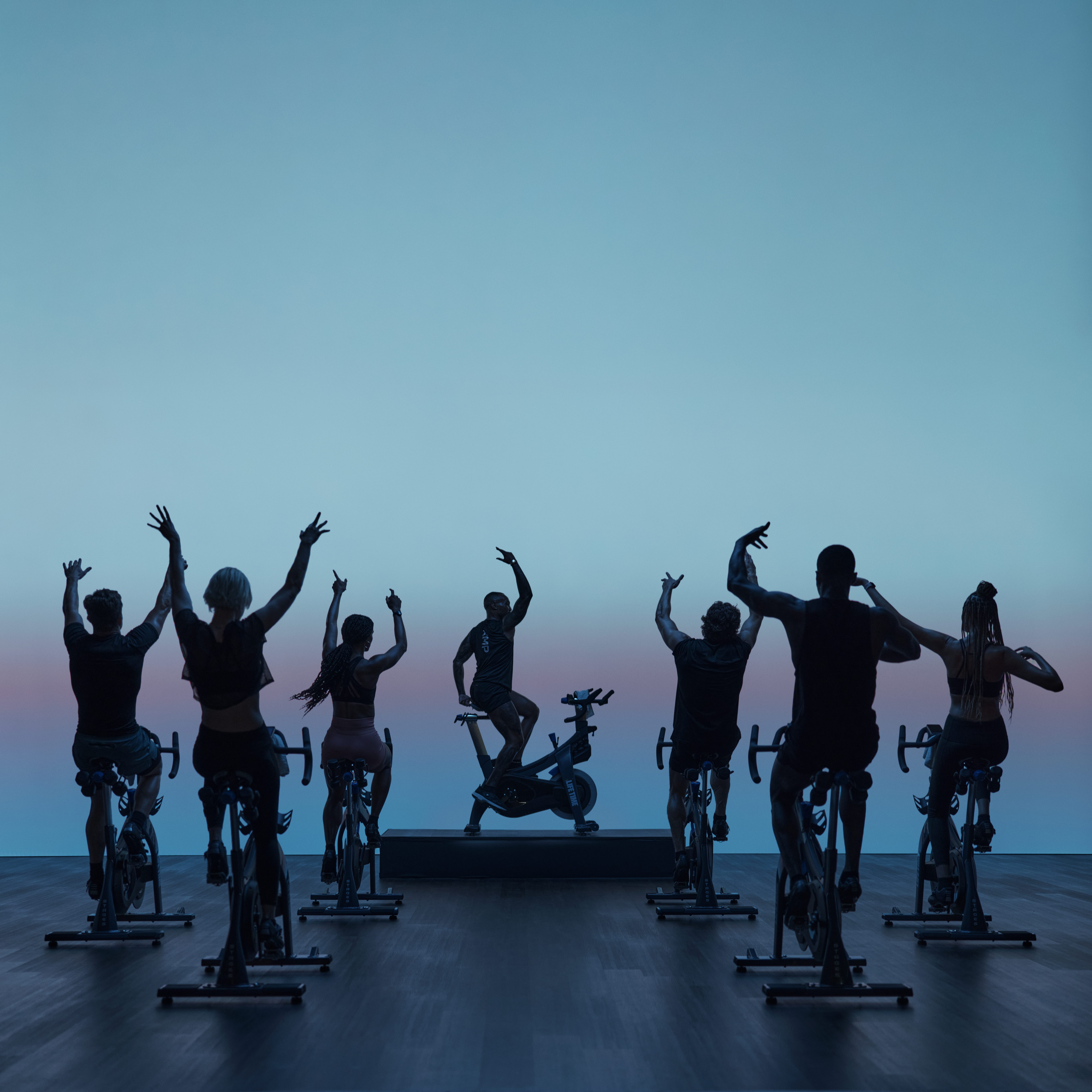 AMP spin class riding together with their hands up