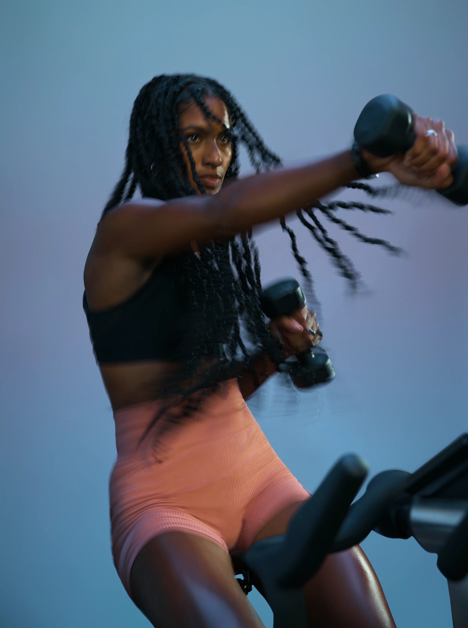 Cyclist actively using a dumbbells during an AMP spin class at Life Time