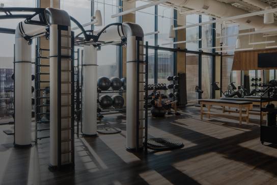 A male lifting weights while laying on his back on a stability ball; Outrace machine in the foreground