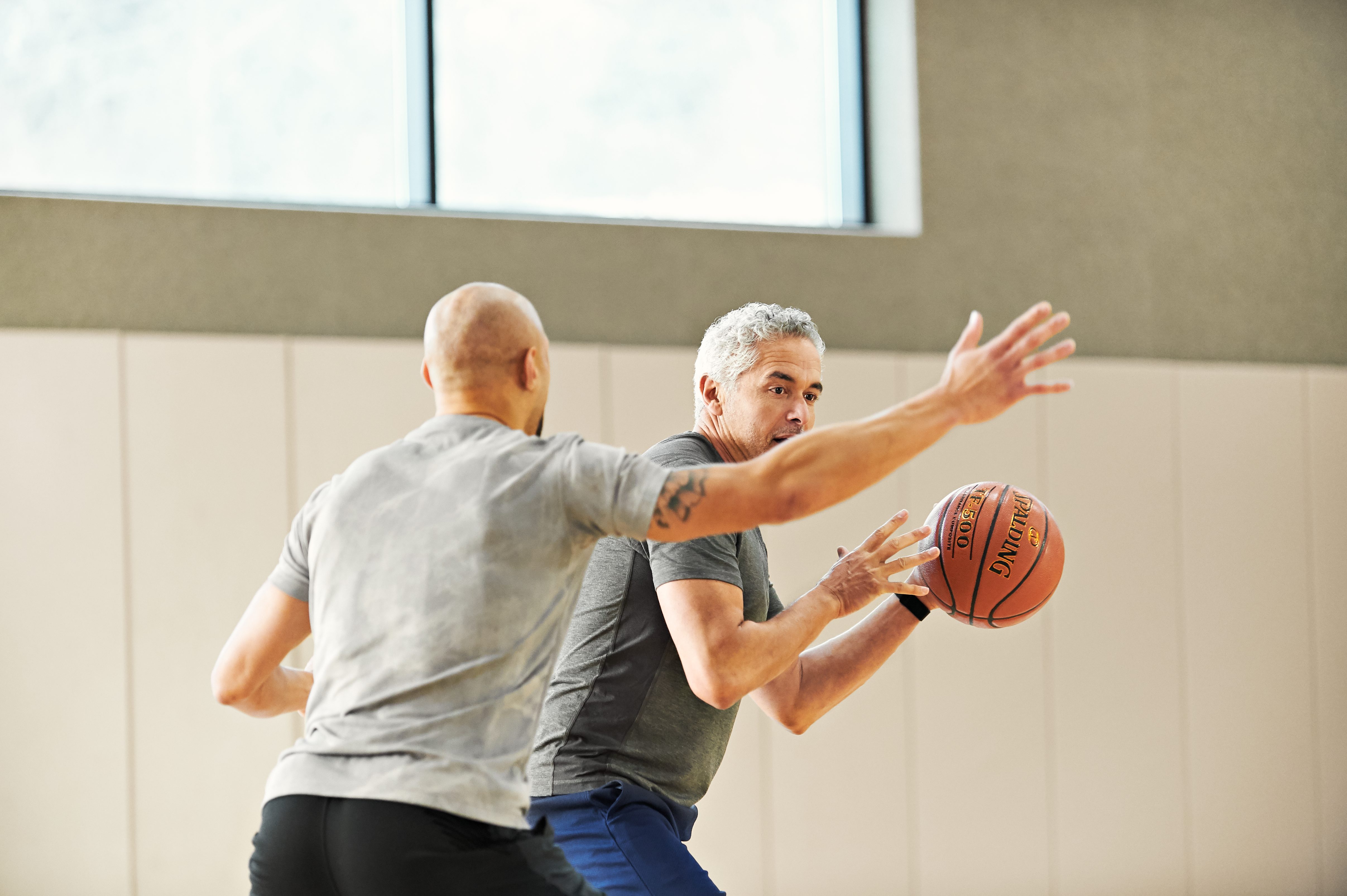 two males playing basketball - blocking/defense