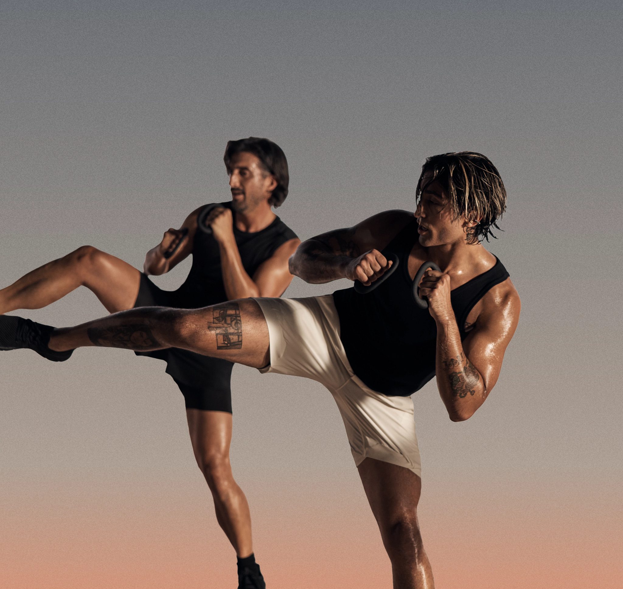 Two Burn kickboxing martial arts class participants in side kick position at Life Time