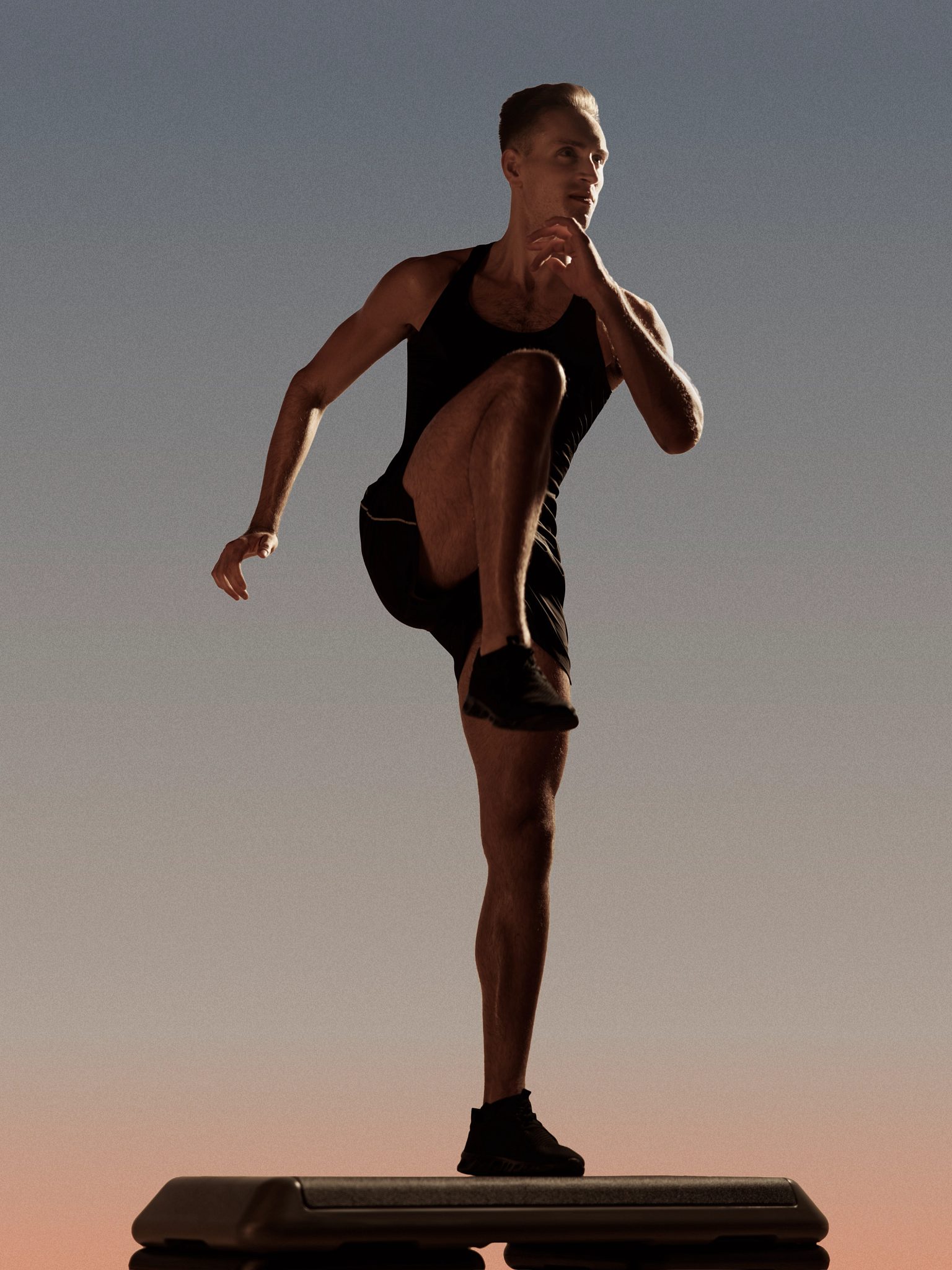 Burn step cardio class member in a high knee lift on top of a step bench at Life Time