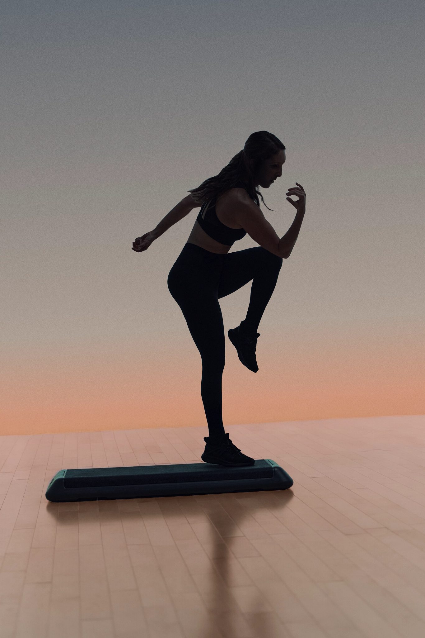 Burn step cardio class participant on a step bench in silhouette at Life Time