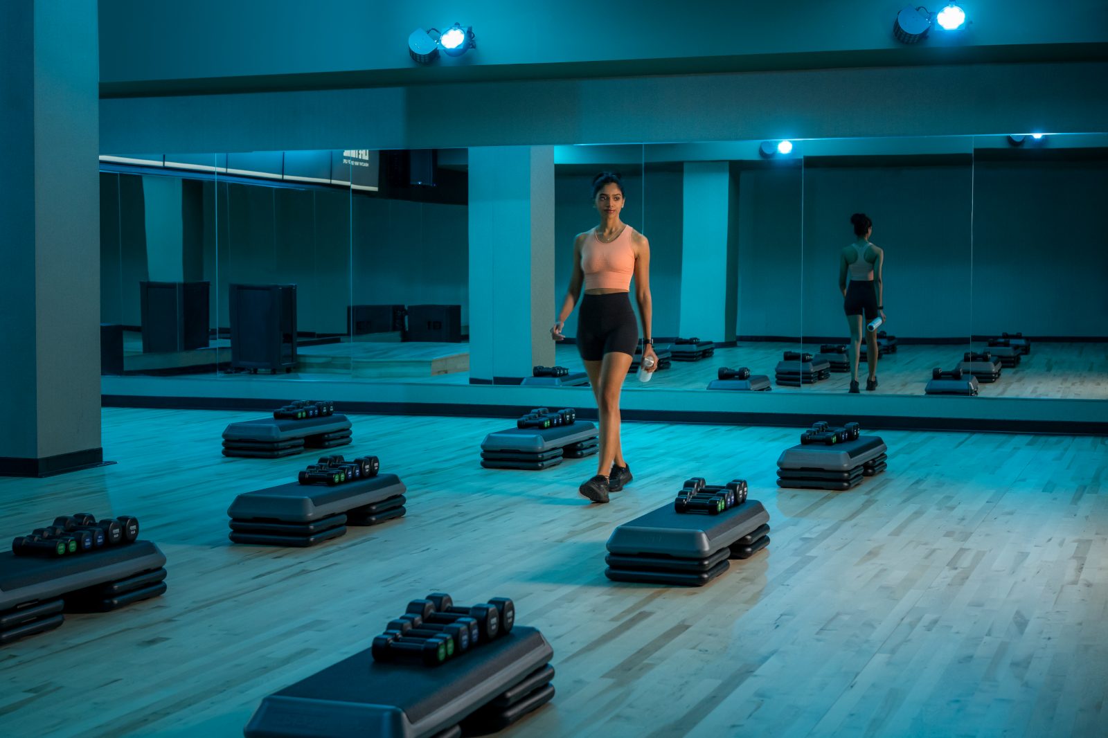 A woman in athletic wear walking through an empty group fitness studio