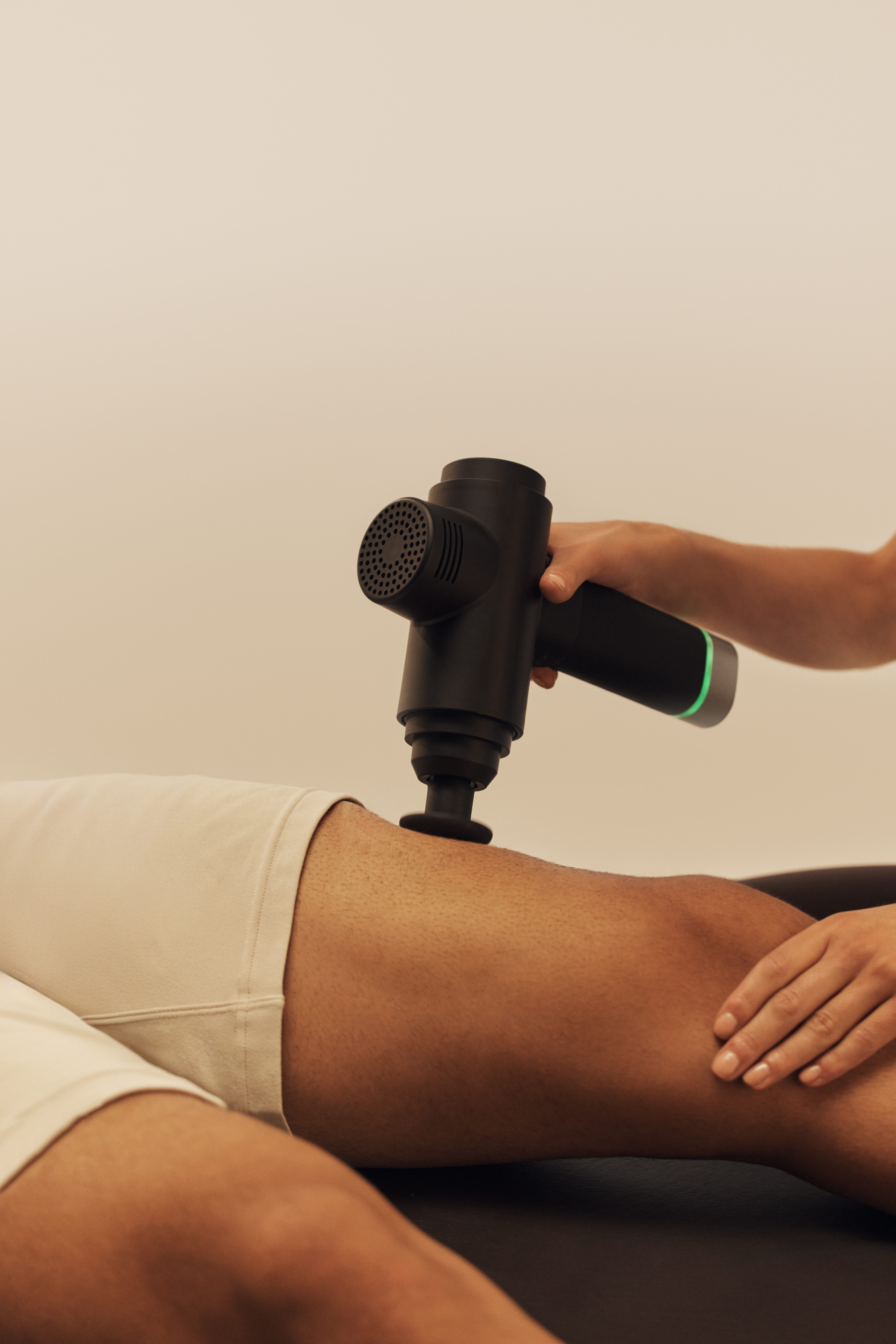 A Dynamic Personal Trainer using a massage gun on her client's leg