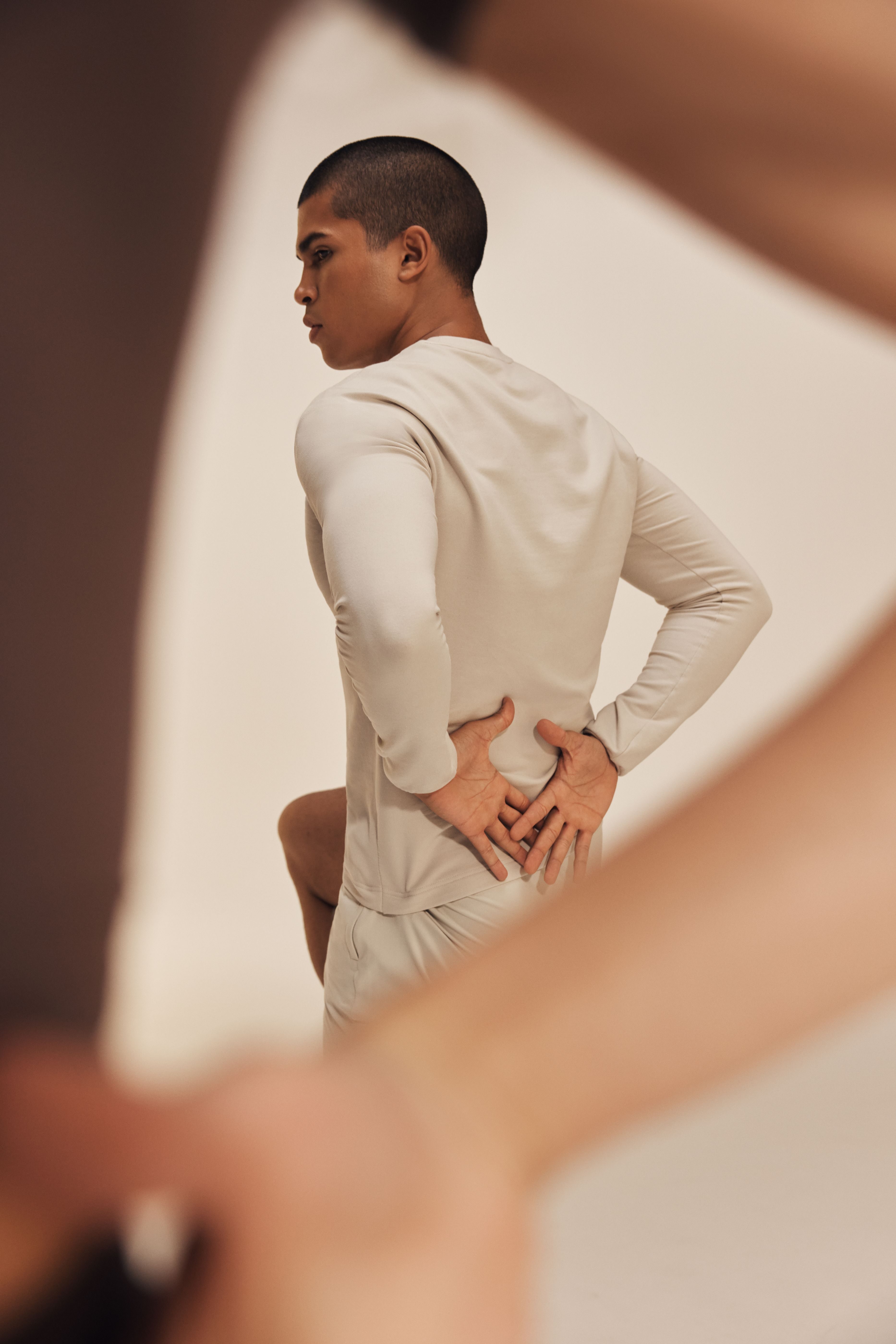 Portrait of a man holding his hands behind his back while balancing on one leg