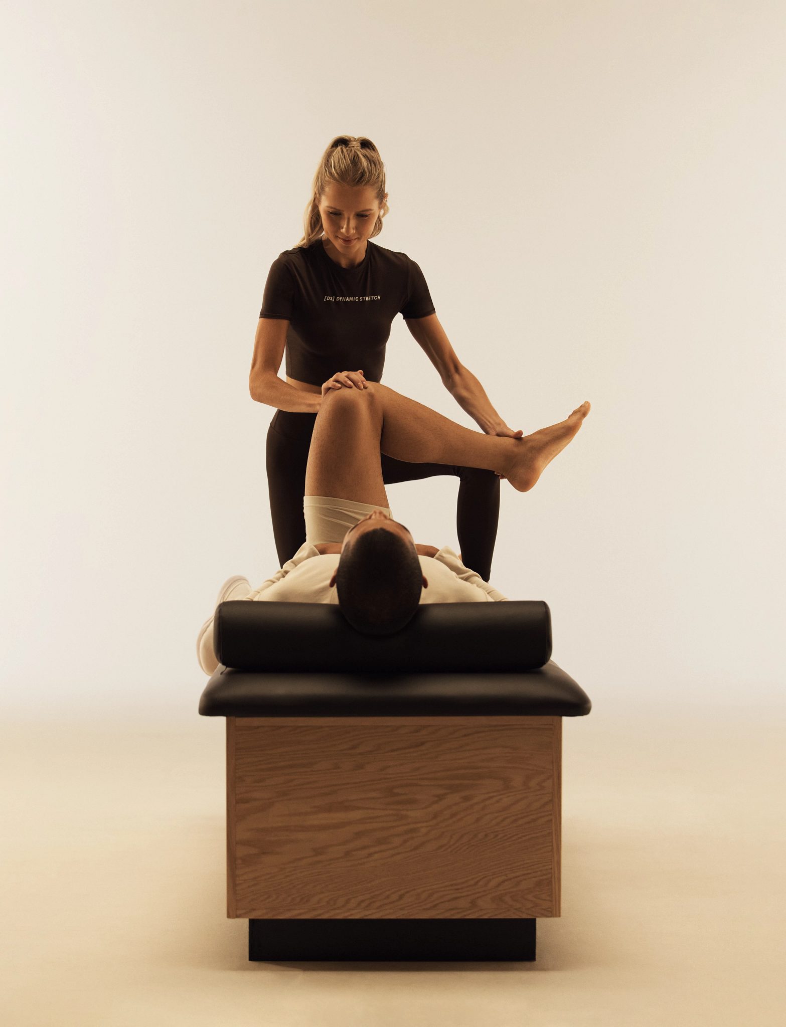 A Life Time trainer stretching a client's leg muscles during a Dynamic Stretch session