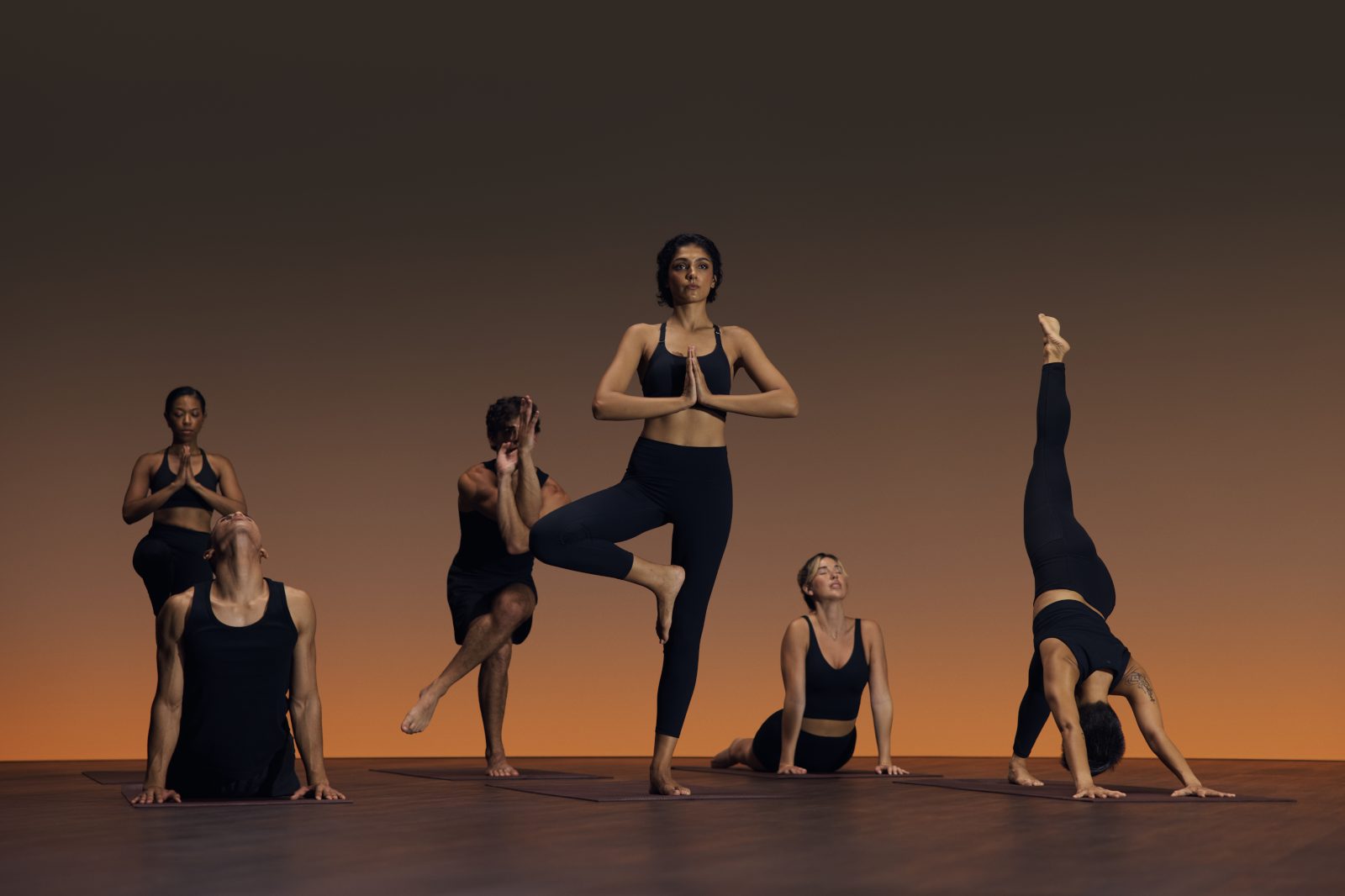 Group of six people in varying yoga poses at a flow yoga class