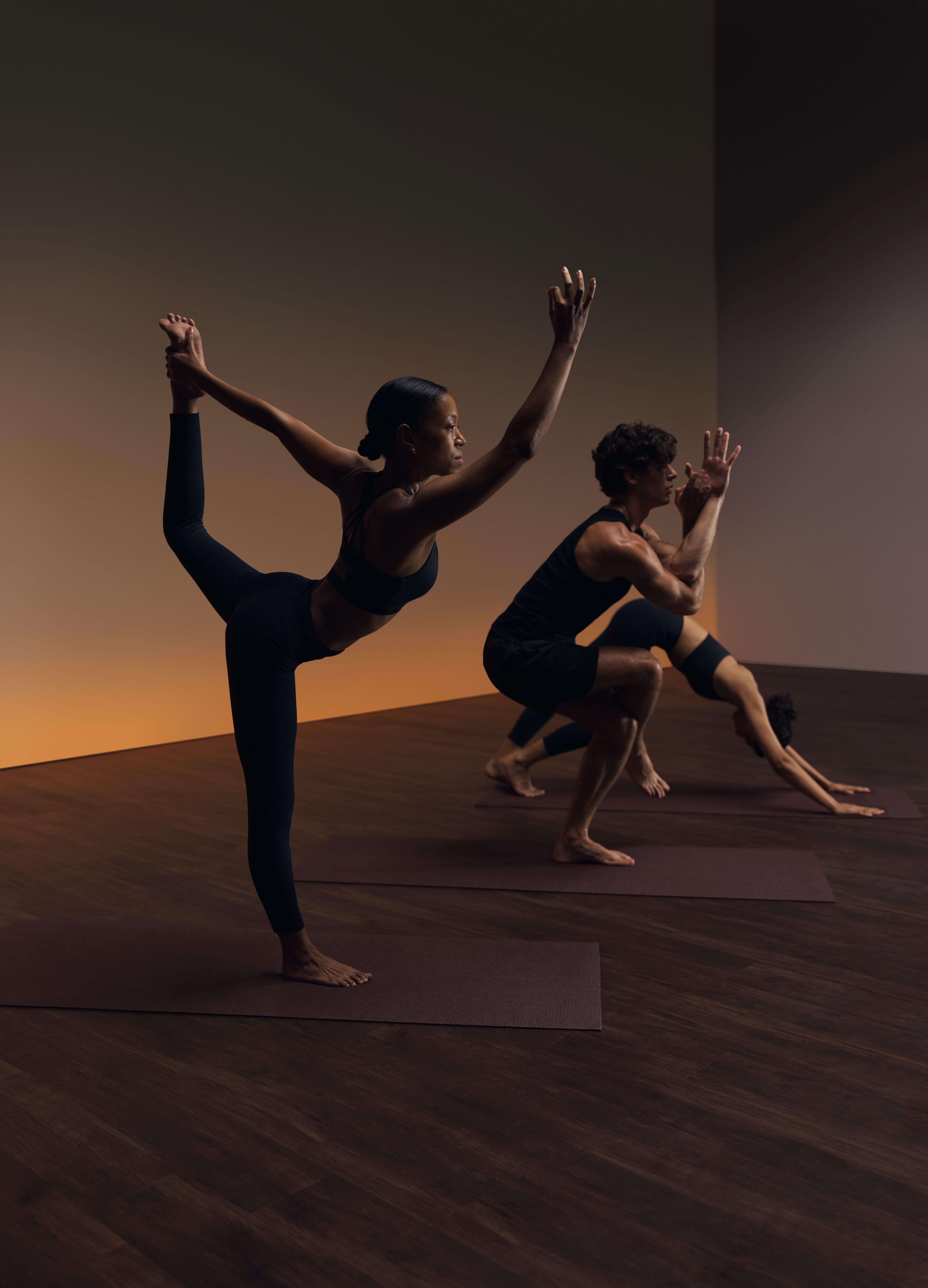 Three people in varying poses at a Life Time flow yoga class