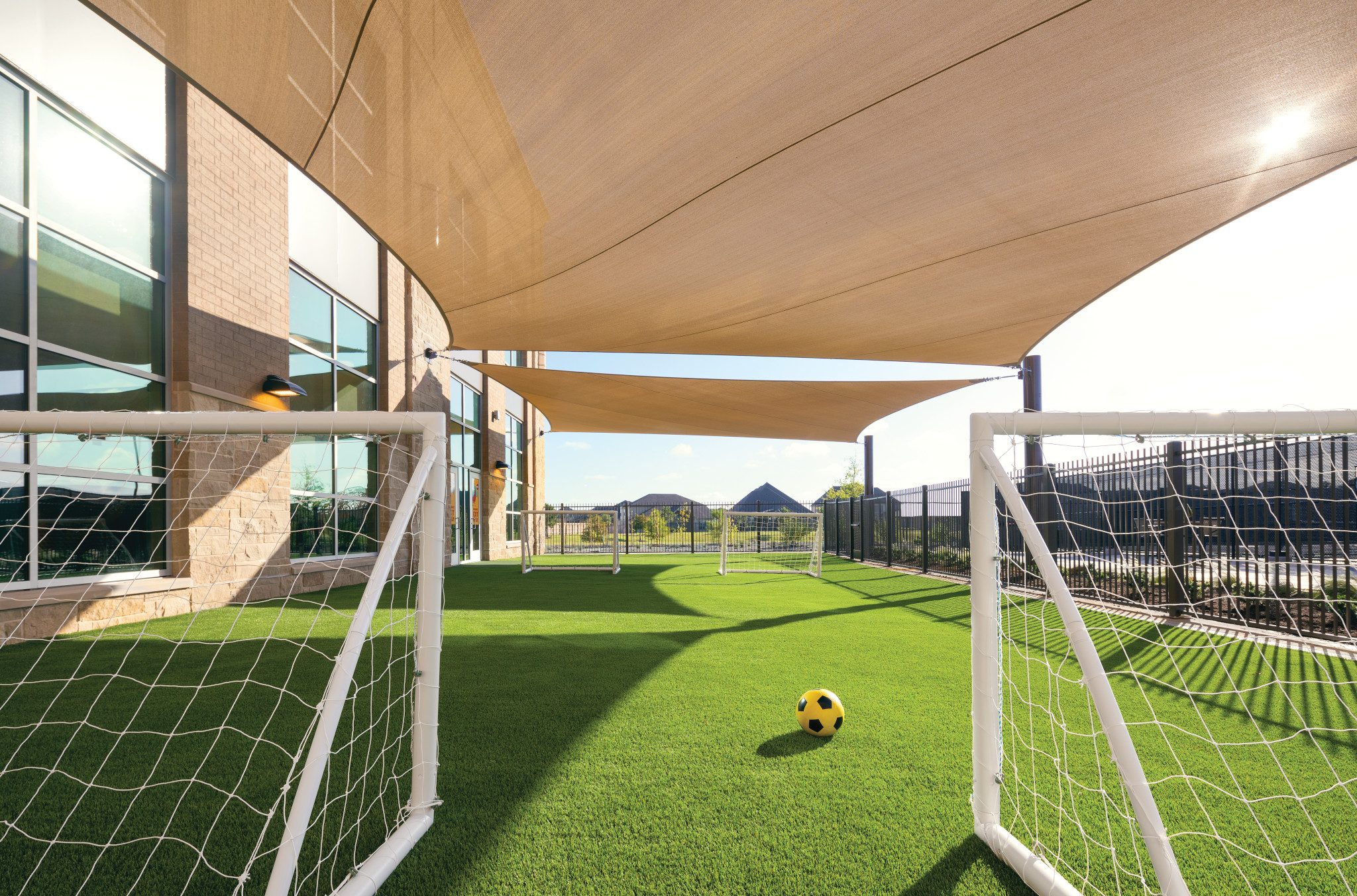 Two soccer goals stand next to each other with a soccer ball in between on an outdoor turf field