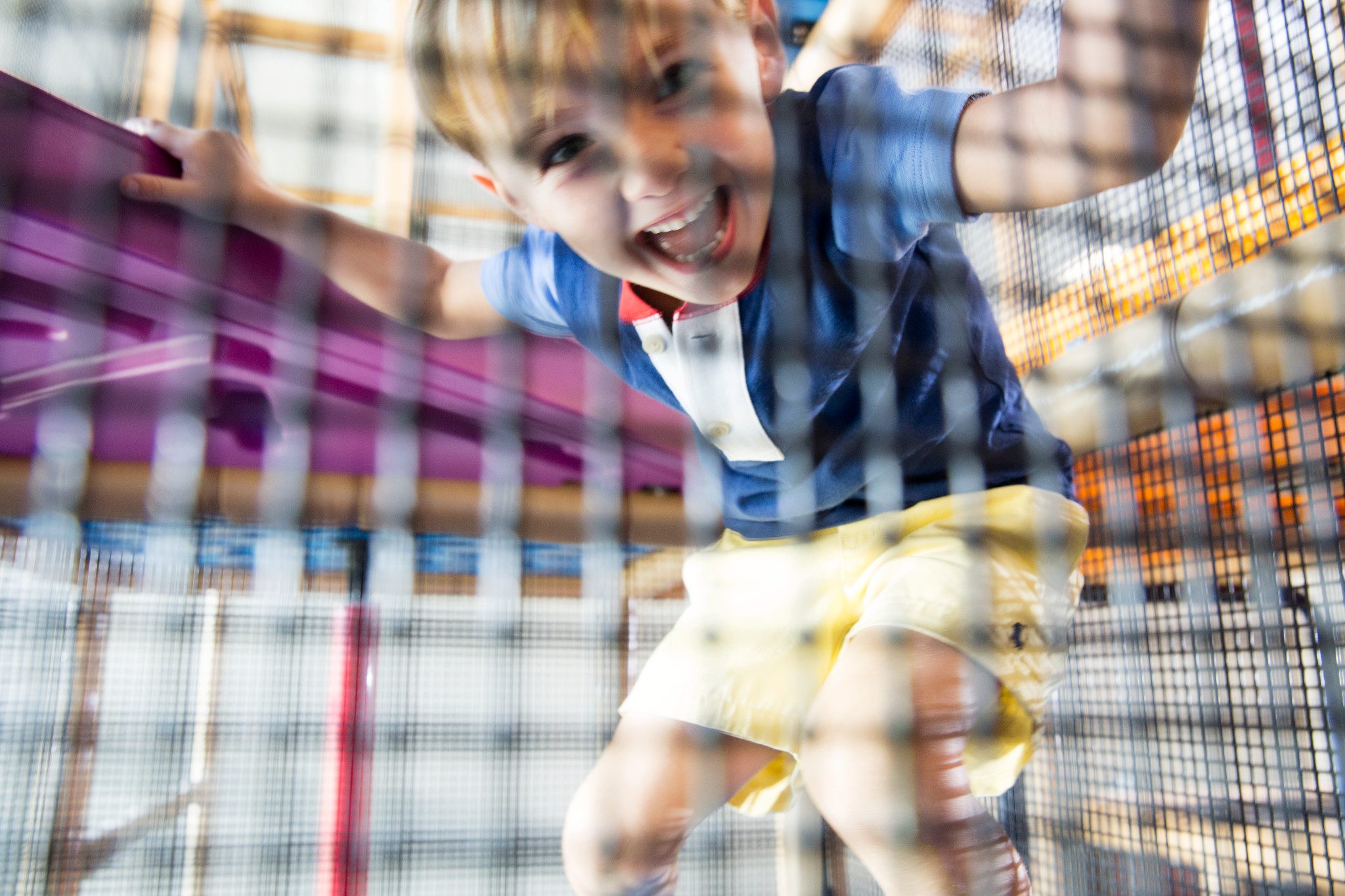 Close view of a male child playing in a netted area on an indoor playground