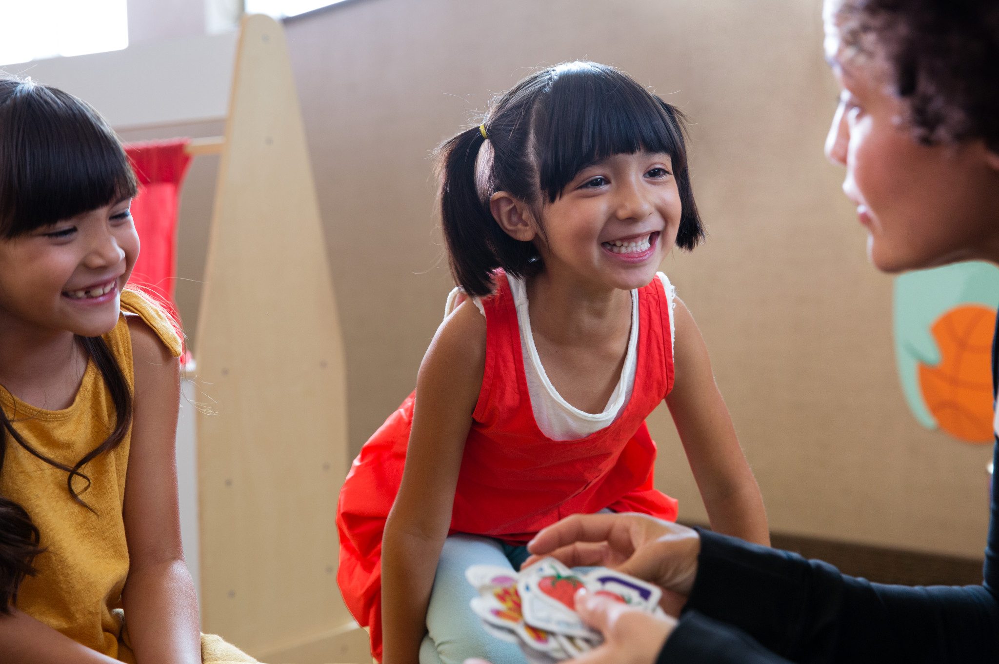 A teacher and two children sit on the floor at Life TIme Kids Academy