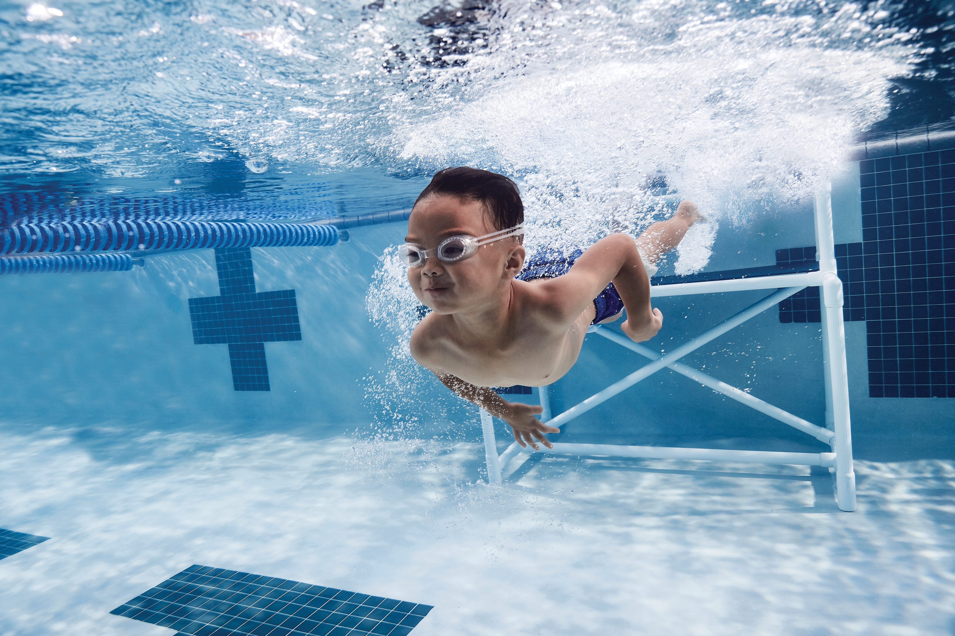 A young boy swims underwater in a pool