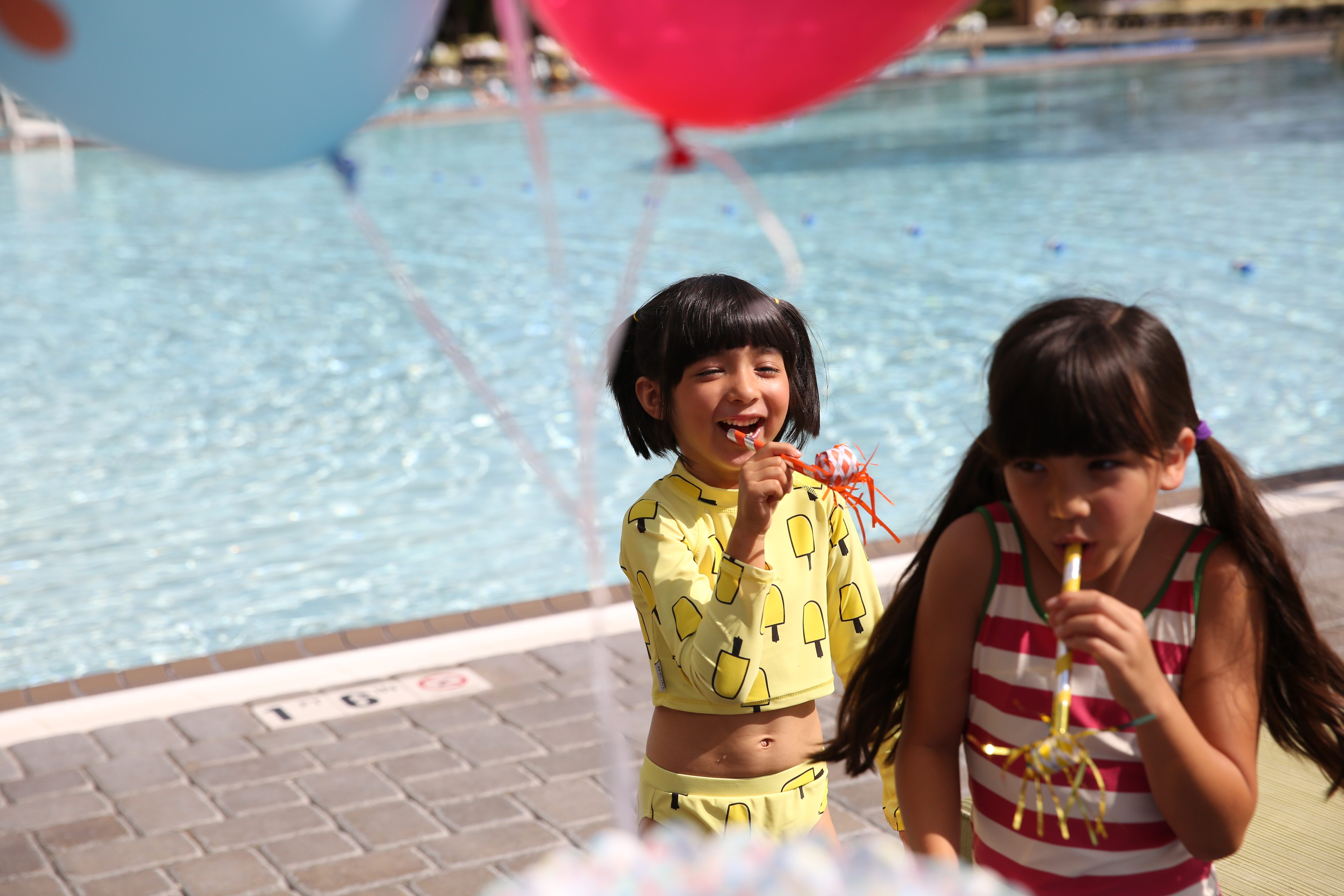 Young children celebrating a birthday by an outdoor pool at Life Time