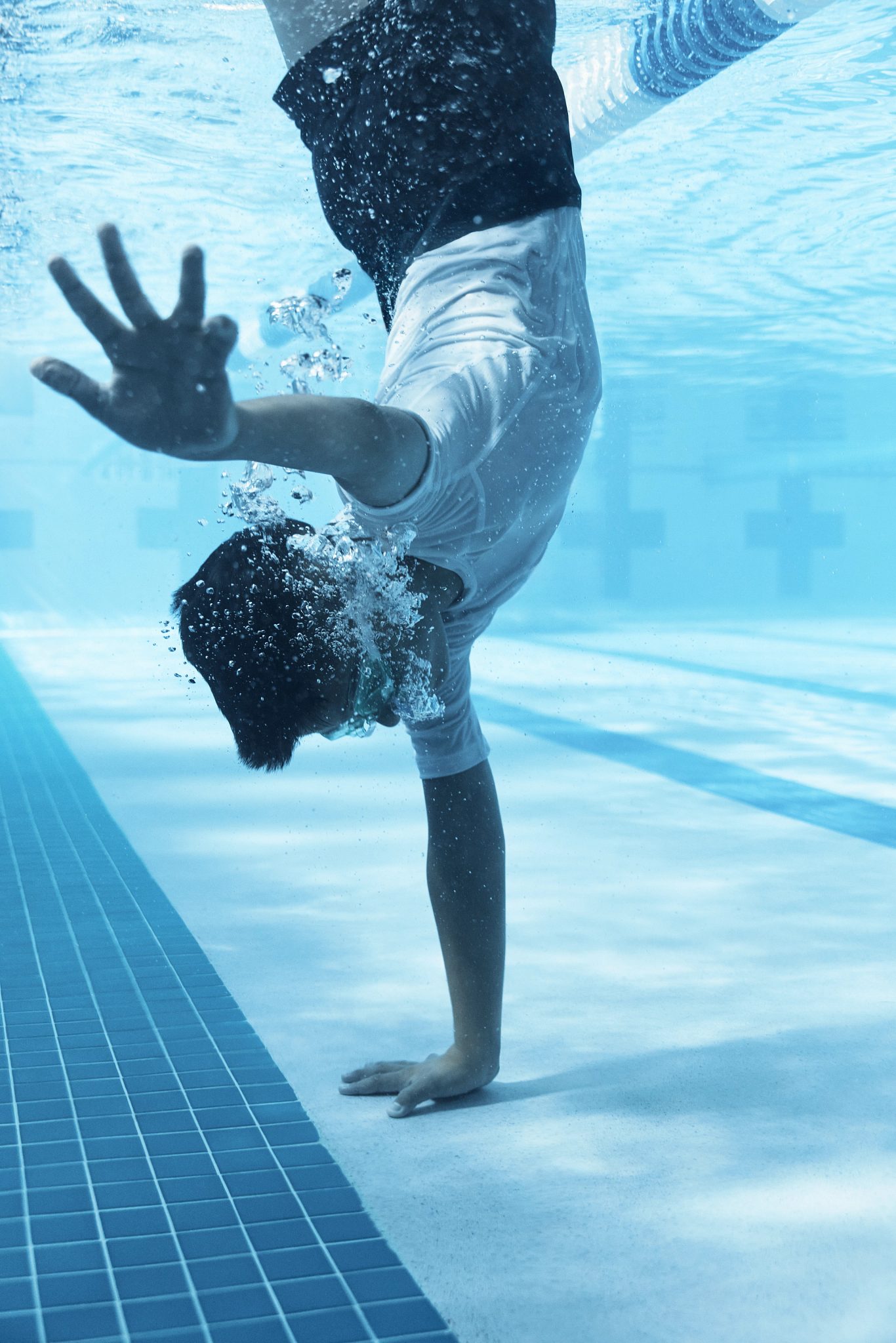 a boy standing on one hand under water