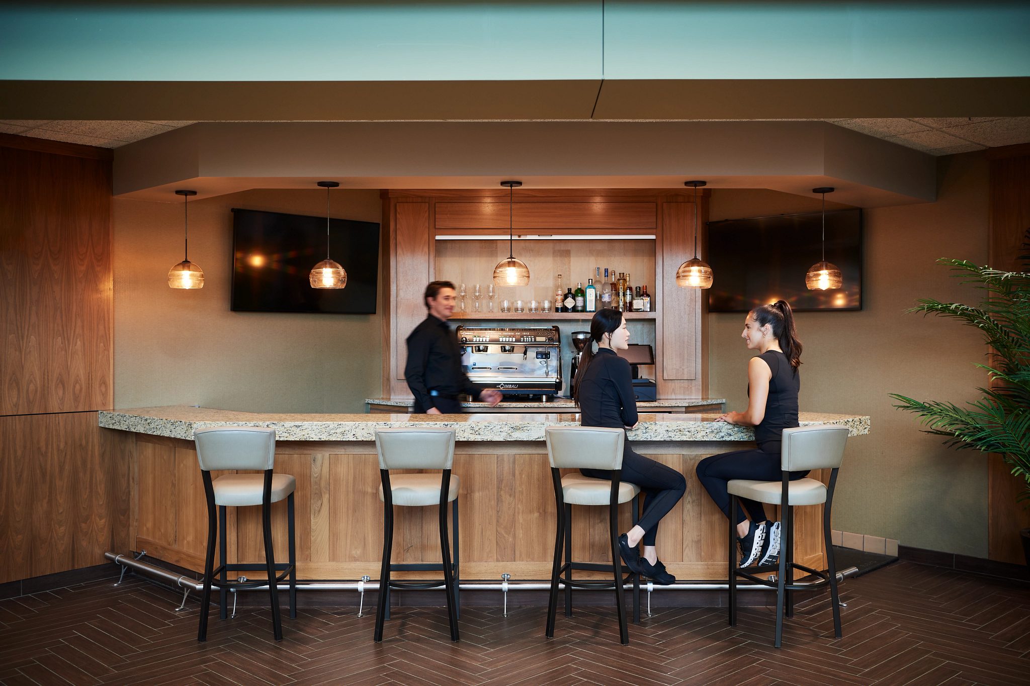 2 femals talk while sitting at a coffee bar