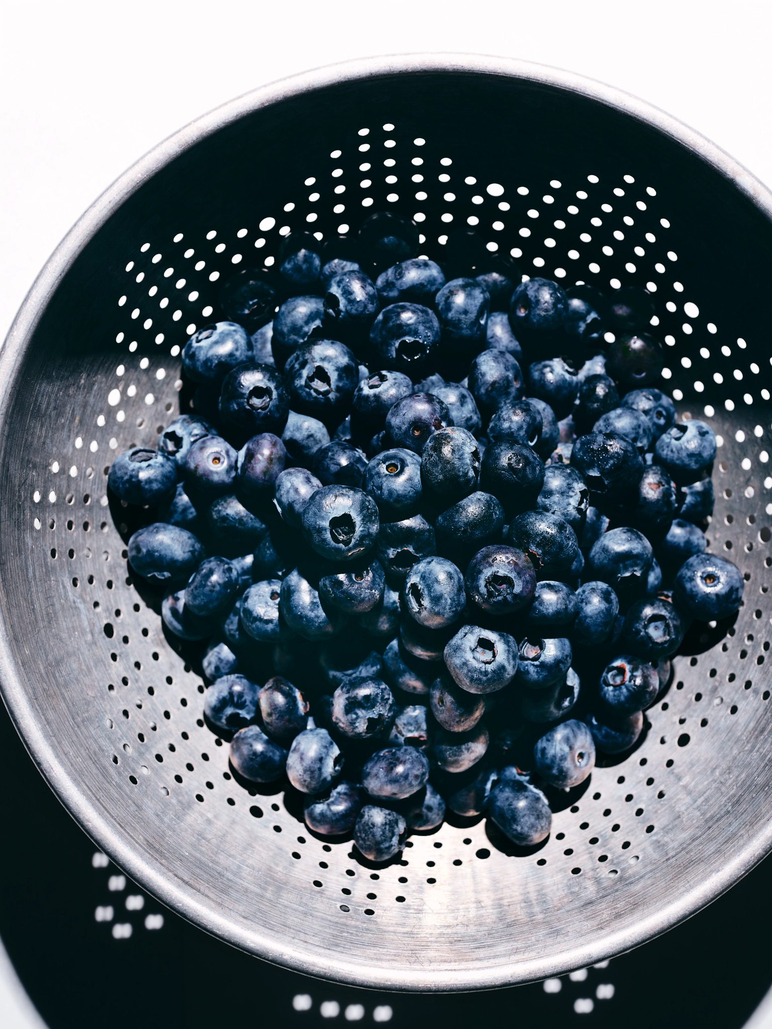 Overhead view of a metal strainer filled with fresh blueberries