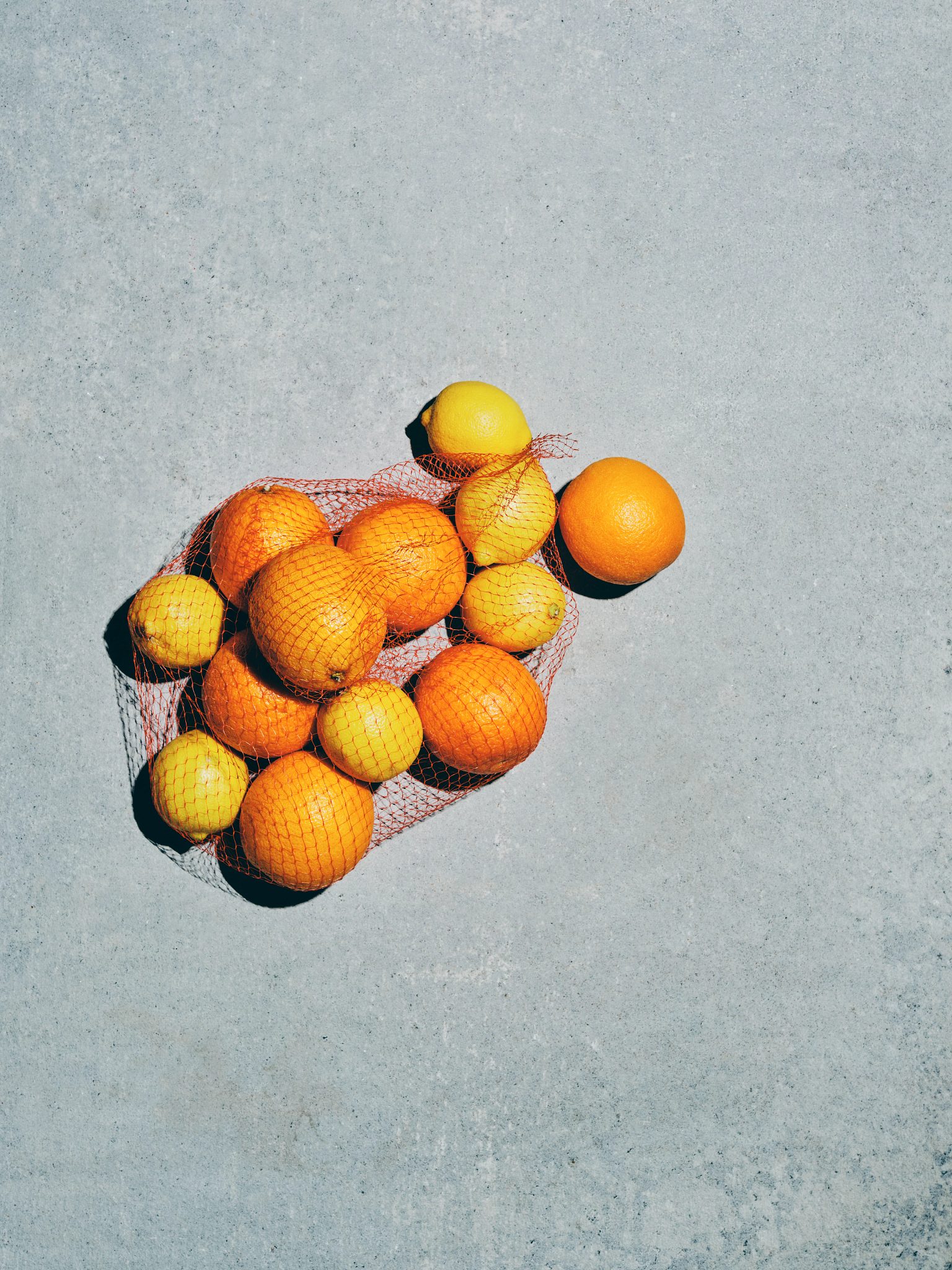 Overhead view of lemons and oranges in a plastic netted bag