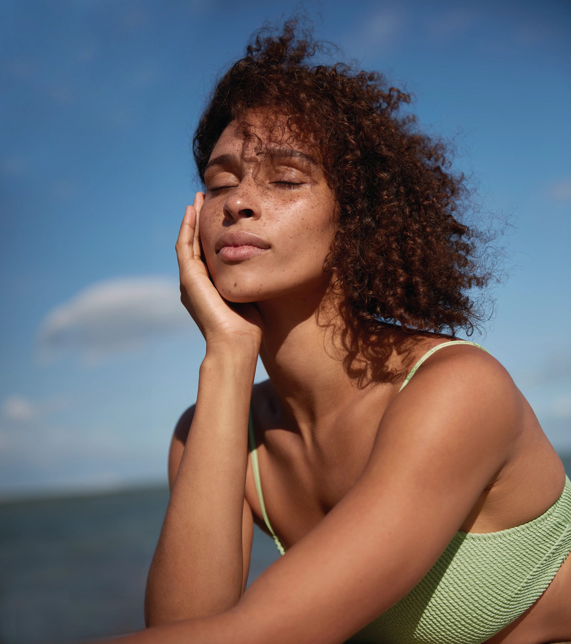 Closeup portrait of a female in a bathing suit enjoying the sun and breeze on her face