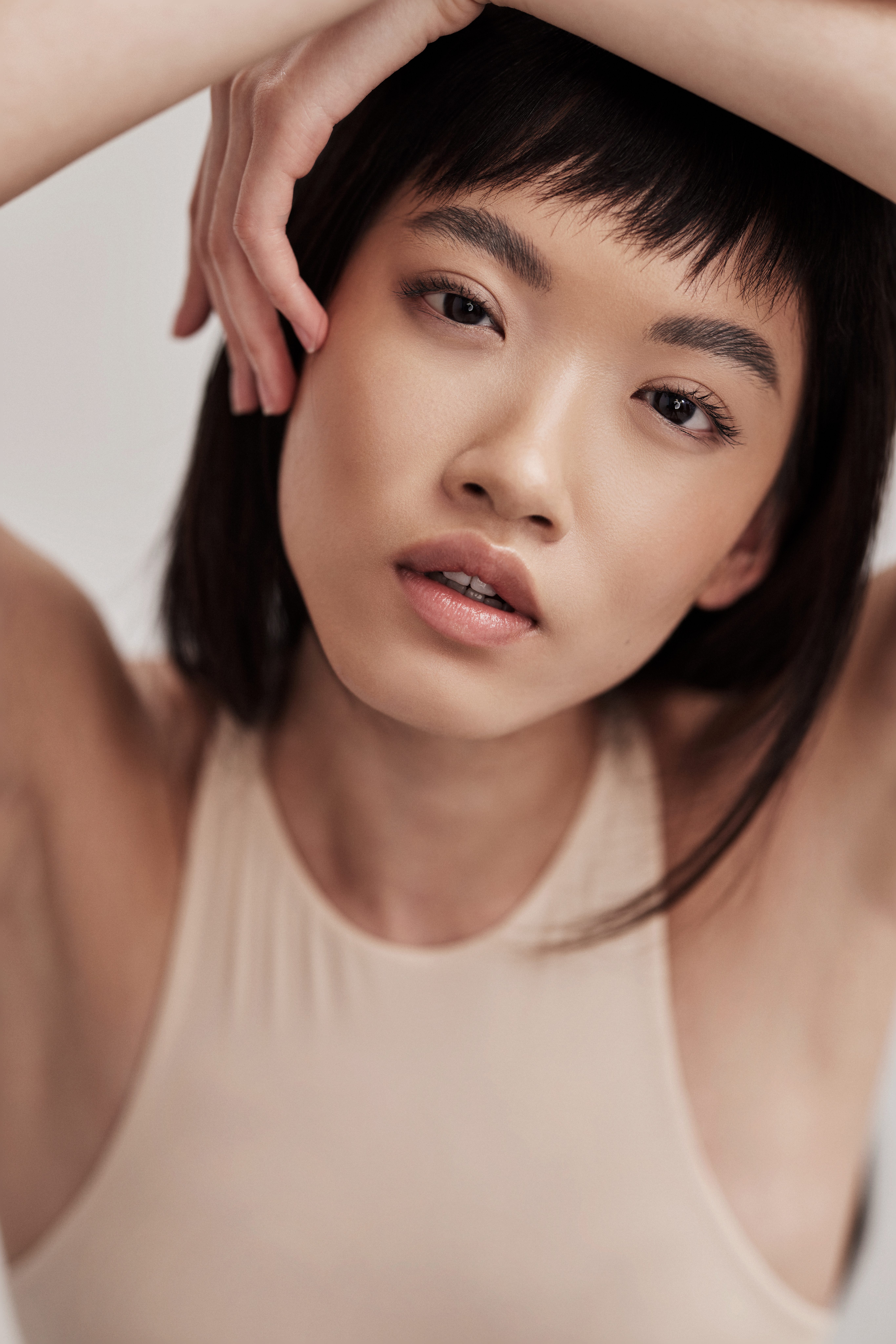 A close-up portrait of an attractive black-haired female with bangs and flawless skin