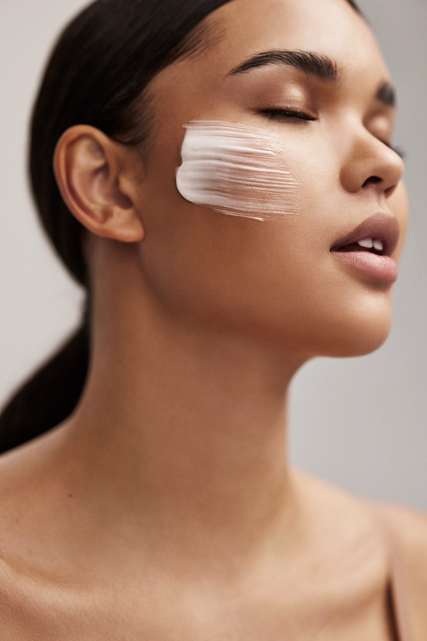 Closeup portrait of an attractive female's face with a brush of lotion across her cheek