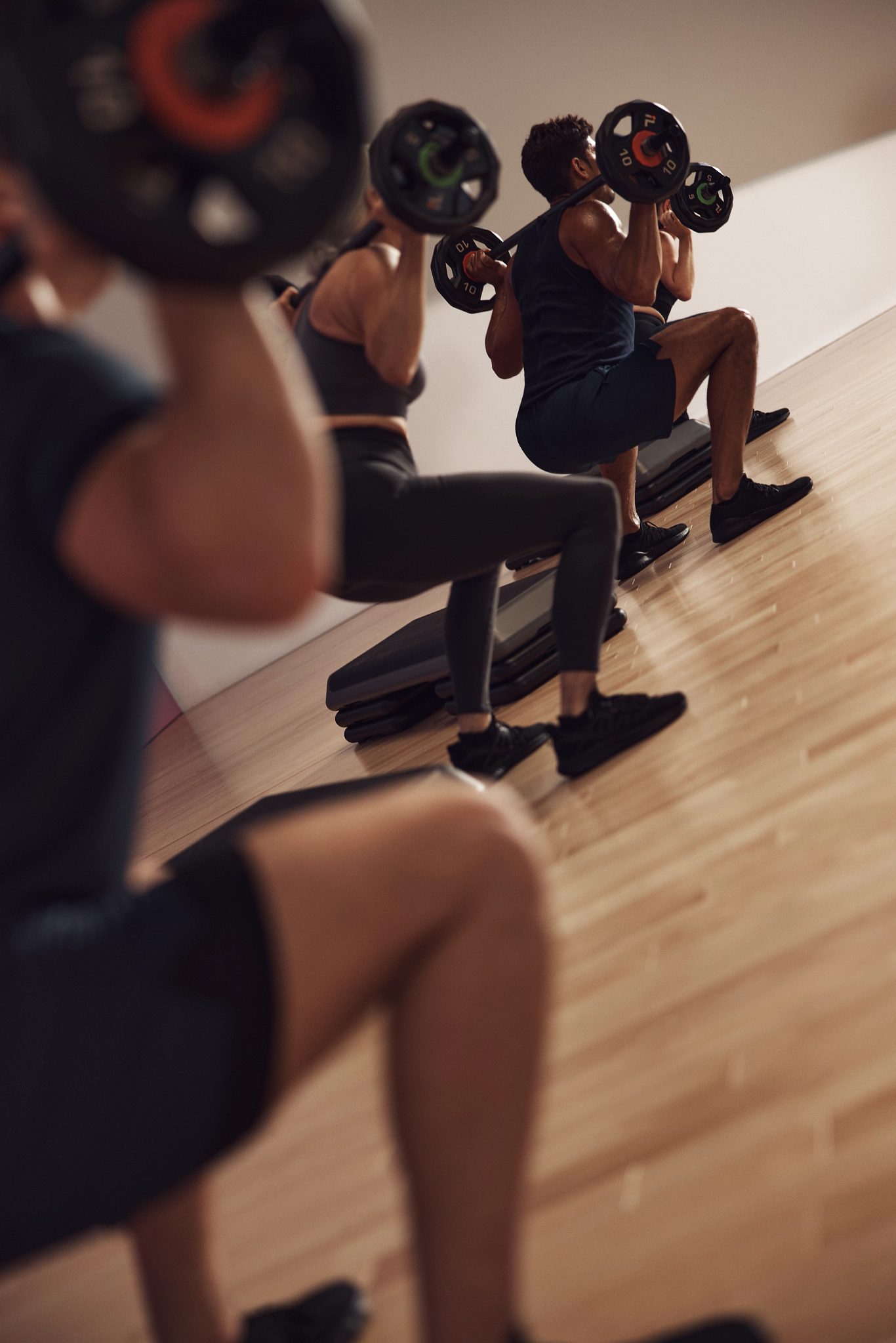 Four people squatting with barbells across shoulders during a Lift strength class at Life Time