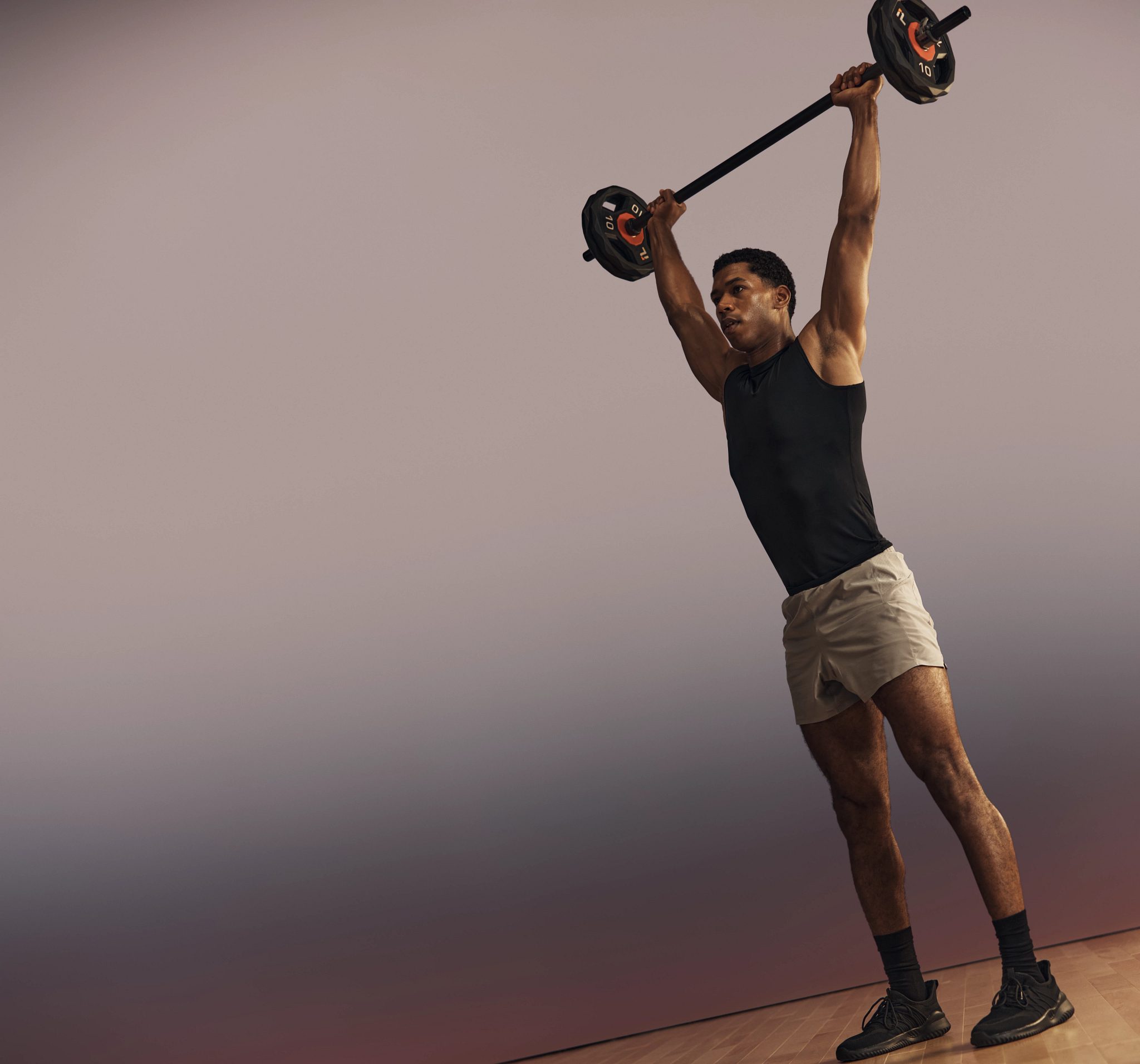 Life Time member lifting a barbell overhead in a strength class