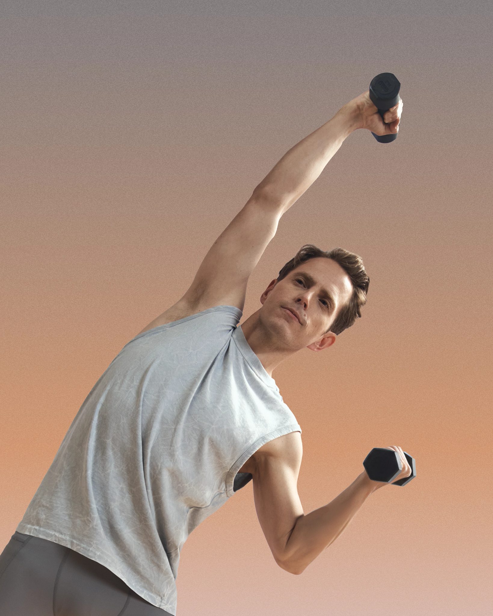 MAT Pilates class participant at Life Time using hand weights and stretching to the side