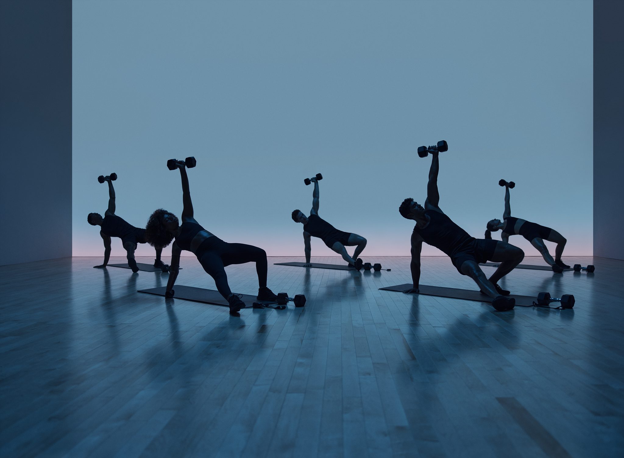 Maxout strength class featuring a group of people in silhouette working out on the floor with barbells