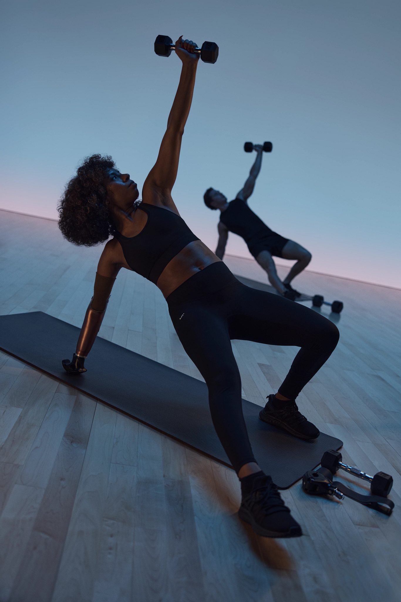 Maxout strength class featuring people in a floor pose with a dumbbell held overhead