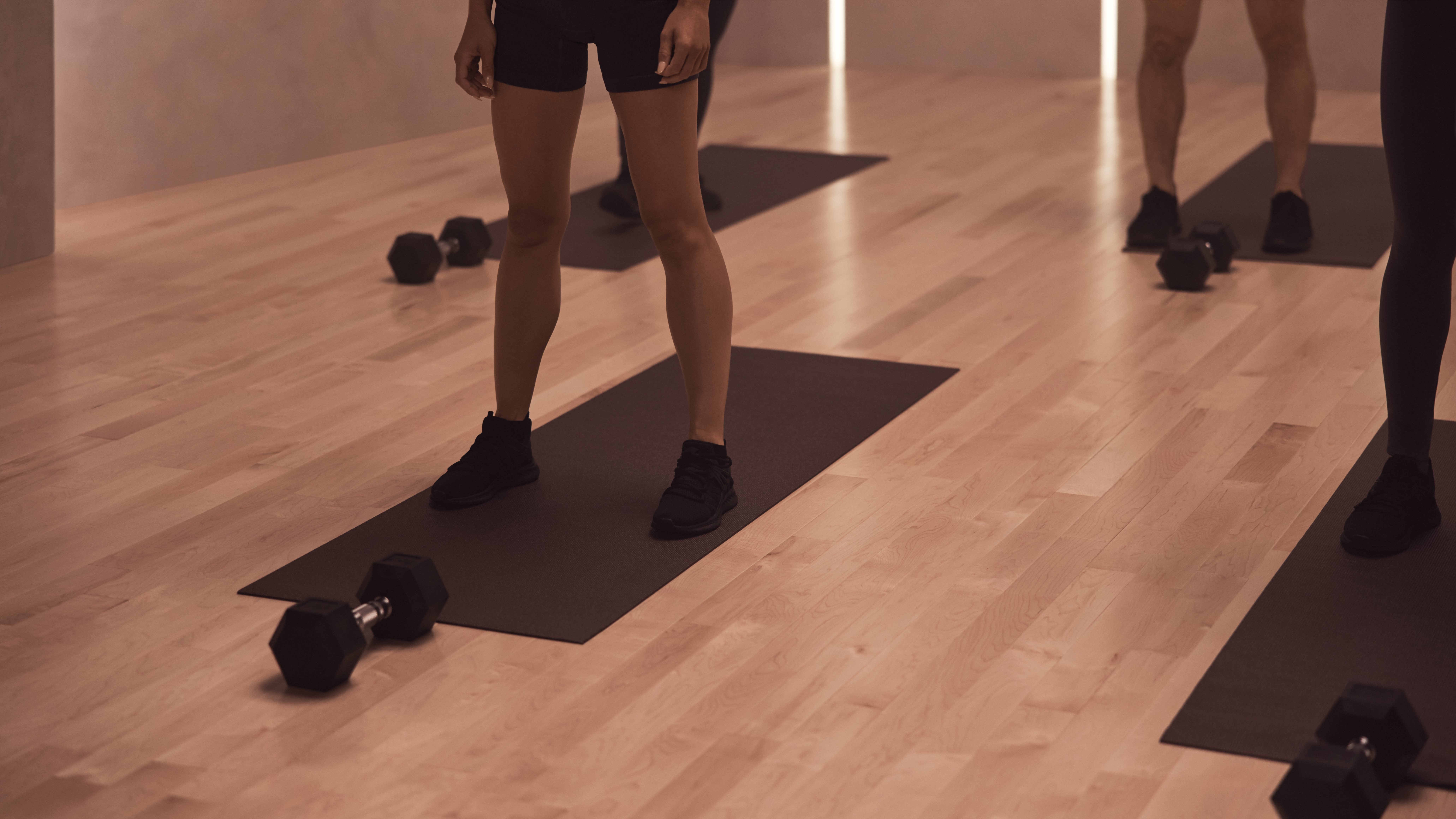 The feet of four Life Time members on their mats at a MB360 boutique group training class