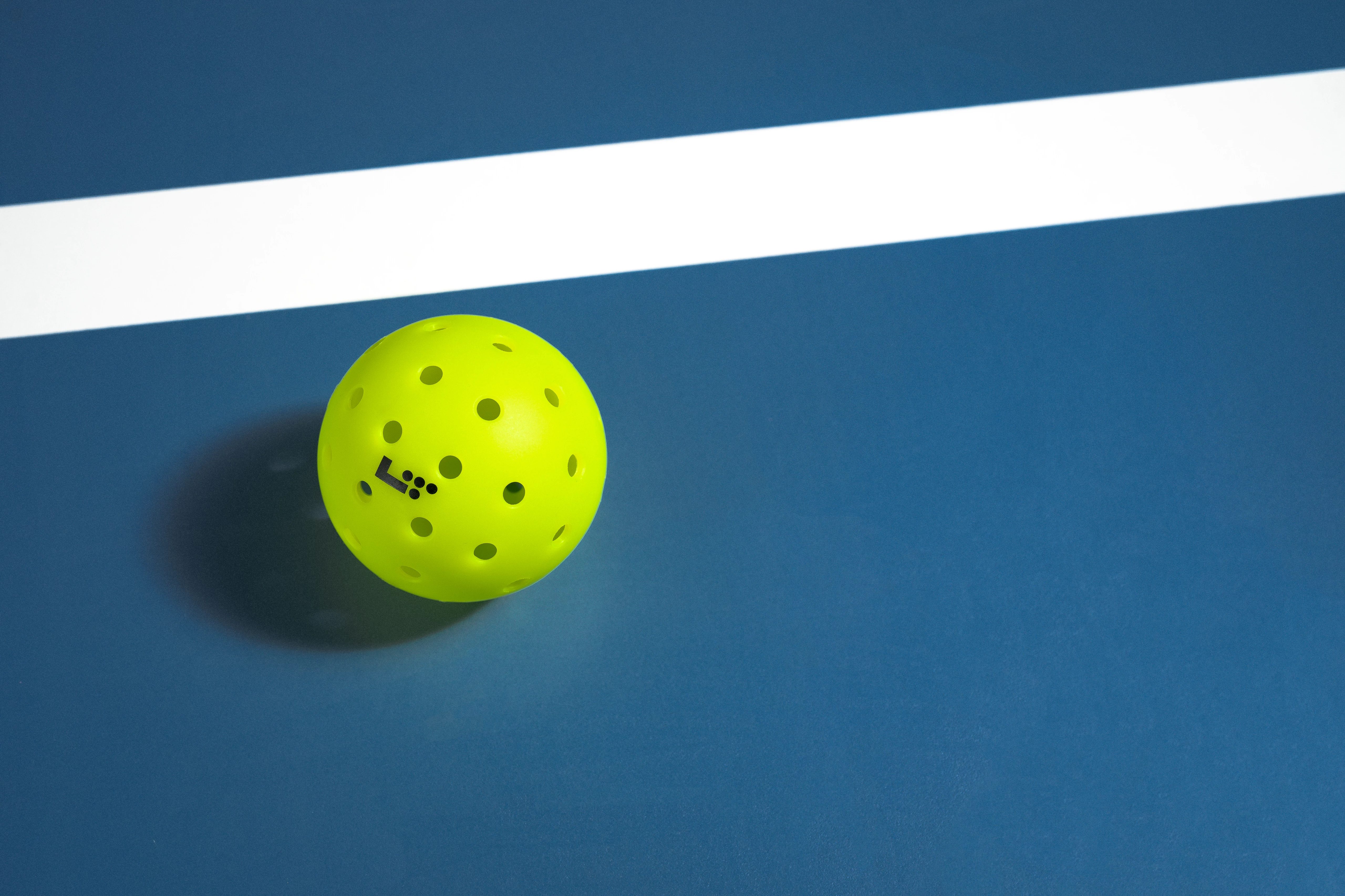 Closeup of a Life Time Branded pickleball placed on a blue court