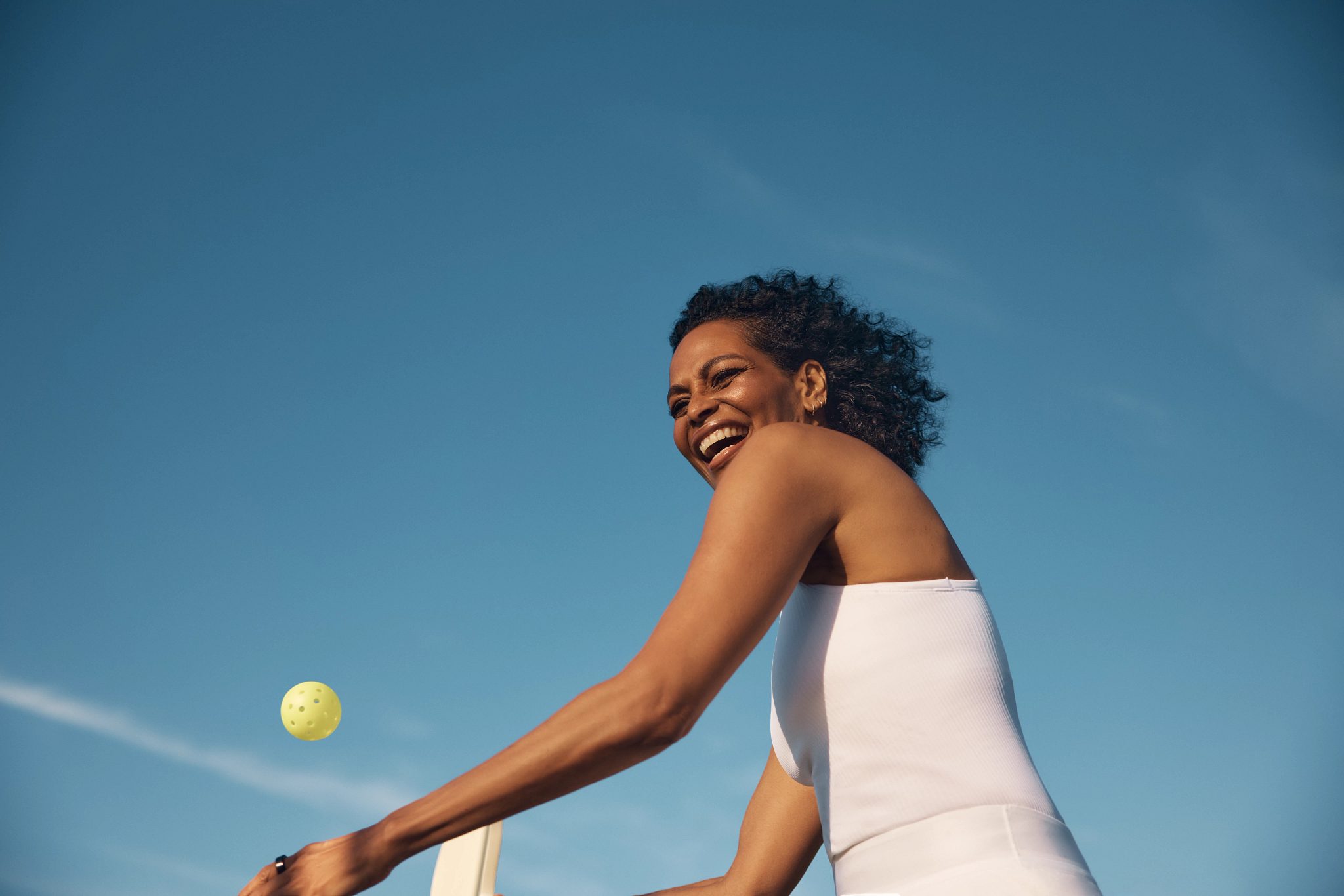 Pickleball player smiling and about to hit a serve