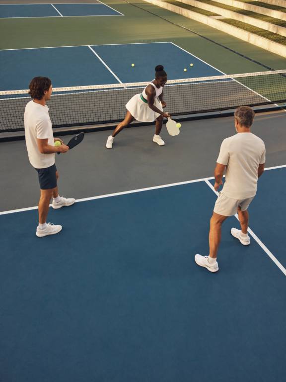Three pickleball players working on their technique on a Life Time court