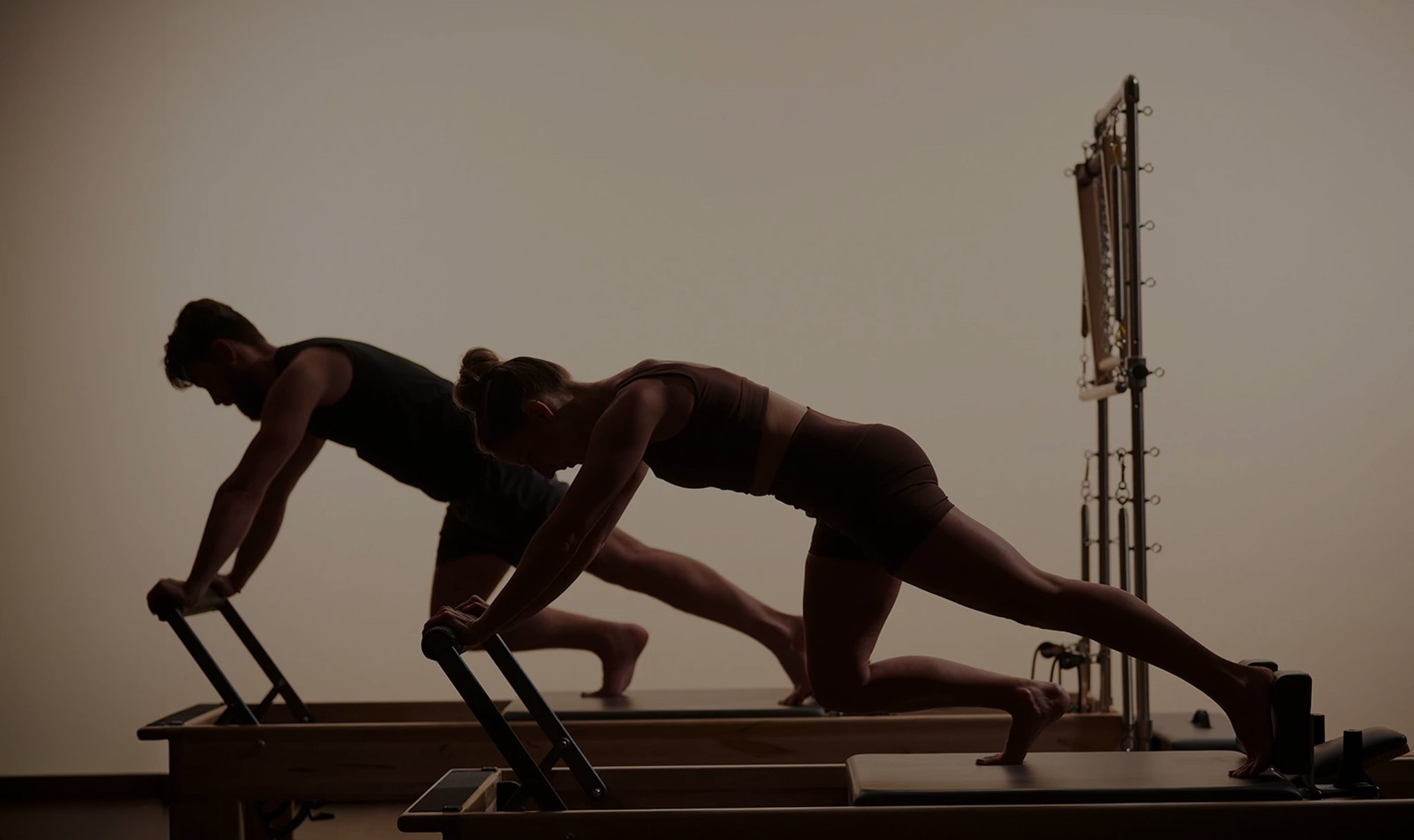 A man and a woman working out on a reformer in a pilates class
