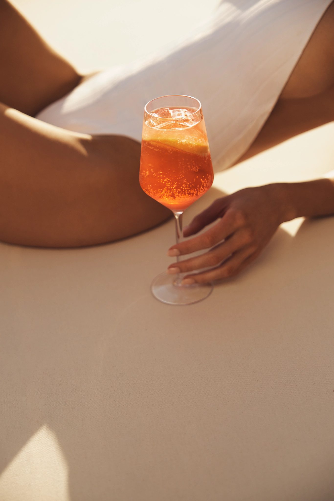 Closeup of a young adult woman wearing a bathing suit while lounging poolside with a drink