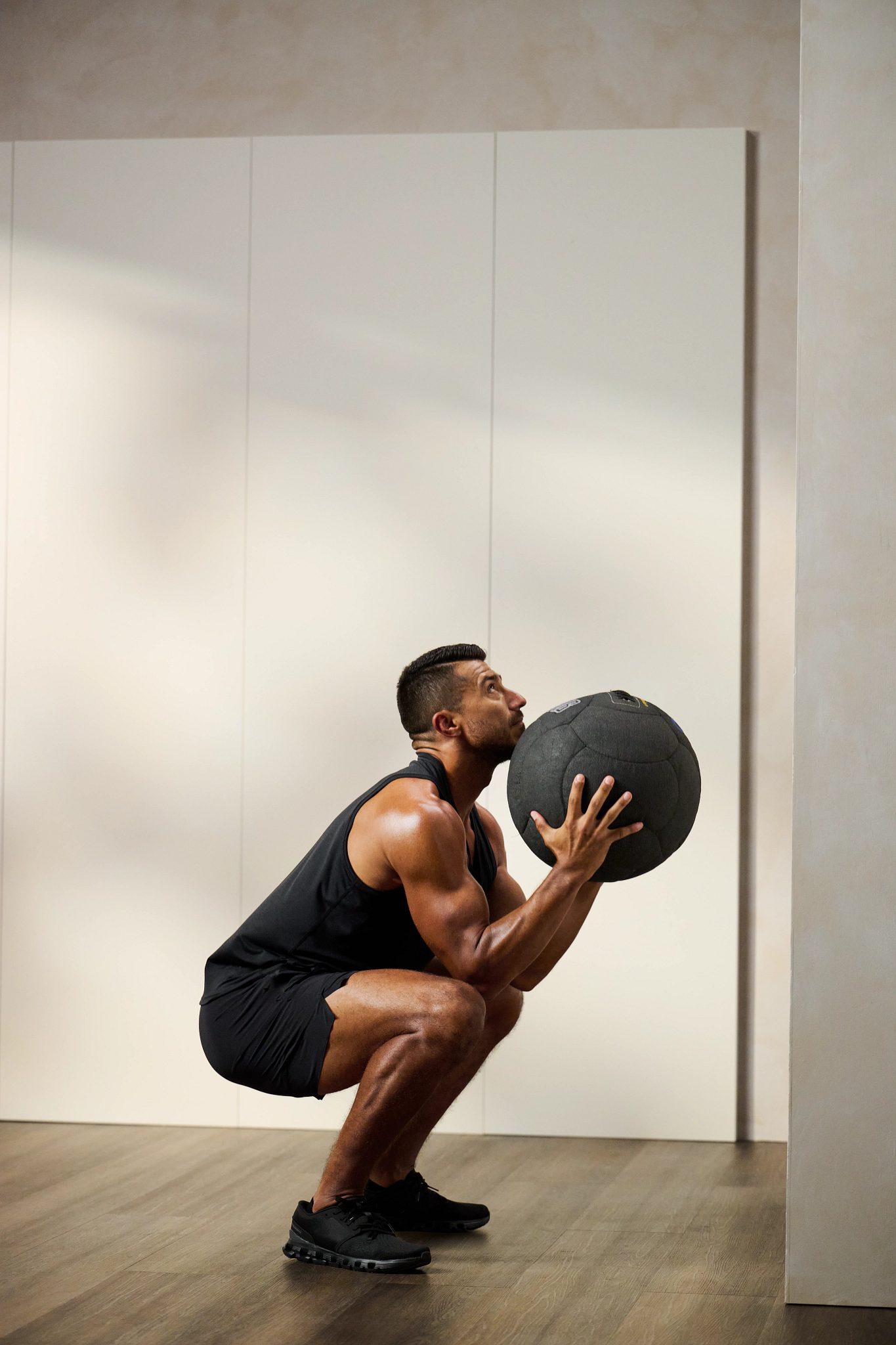 man squatting holding a medicine ball